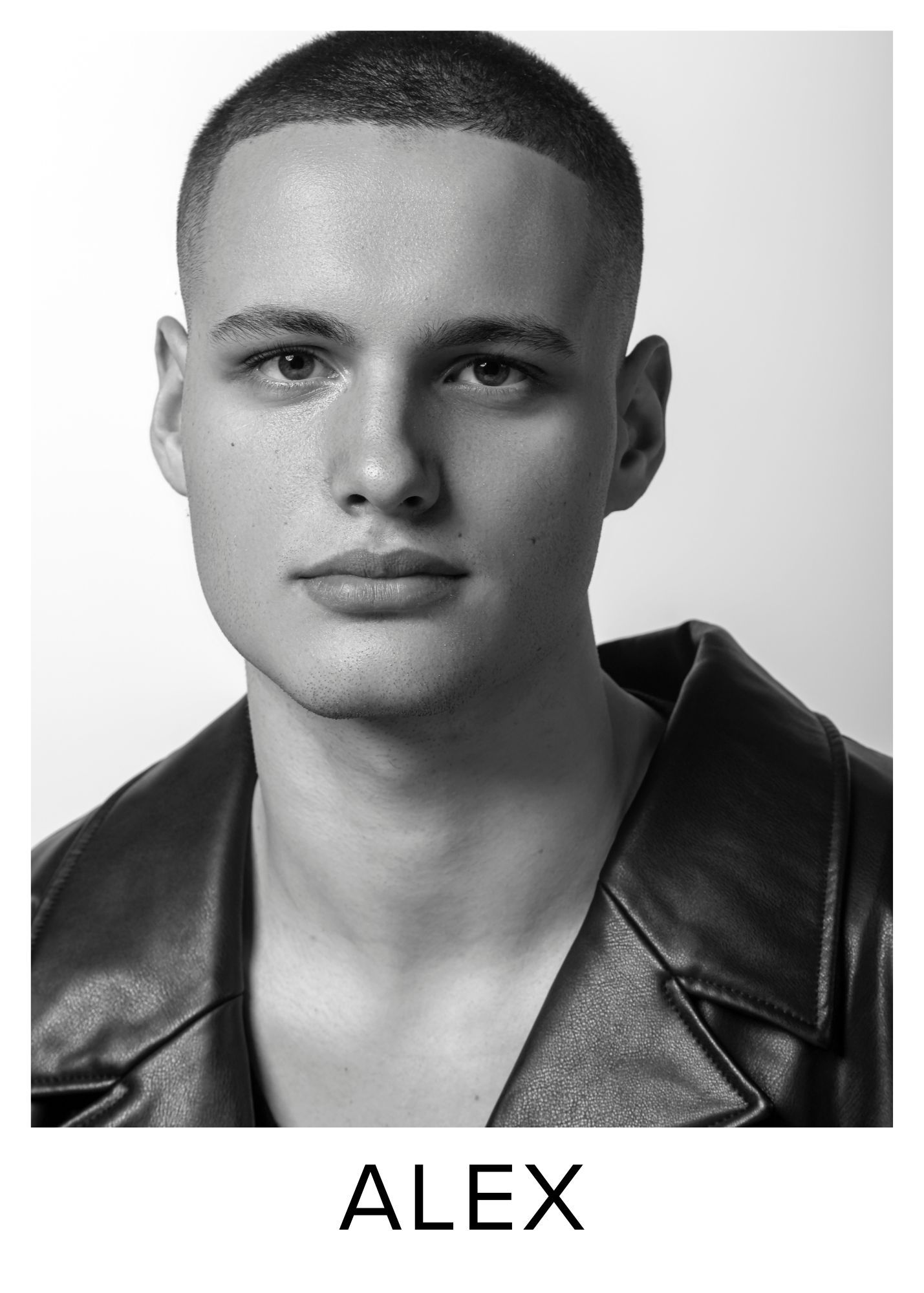 Black and white headshot of Alex, a young male model with a buzz cut wearing a leather jacket.