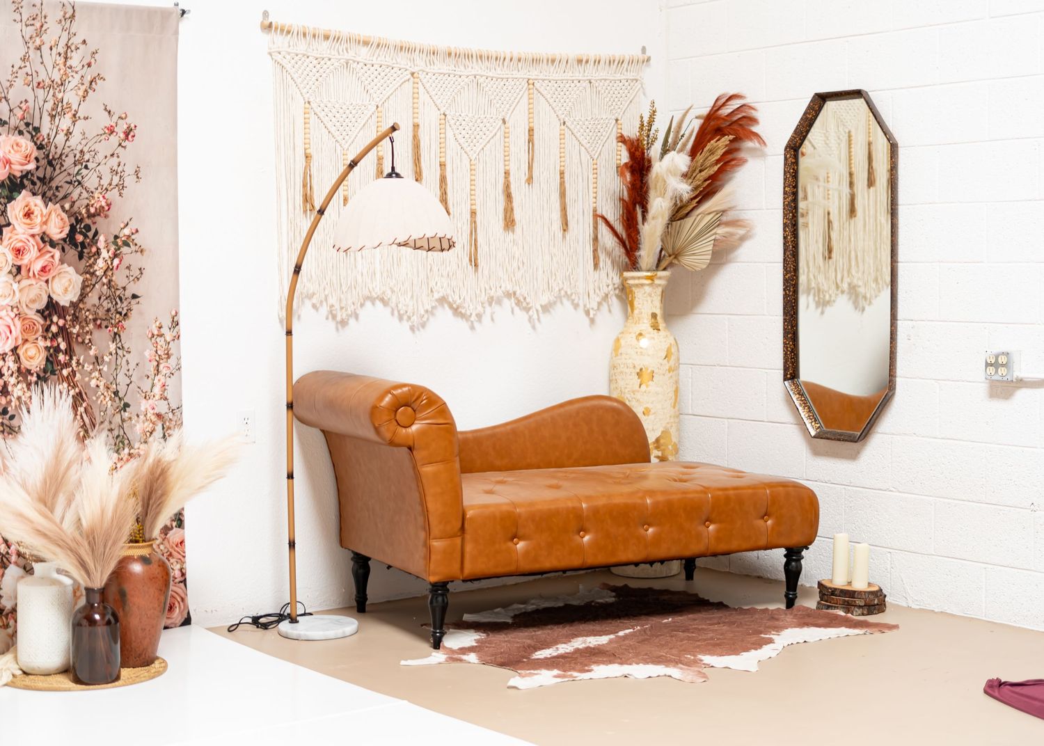 Boho studio setup with tan tufted chaise lounge, macrame wall hanging, and dried floral decor.