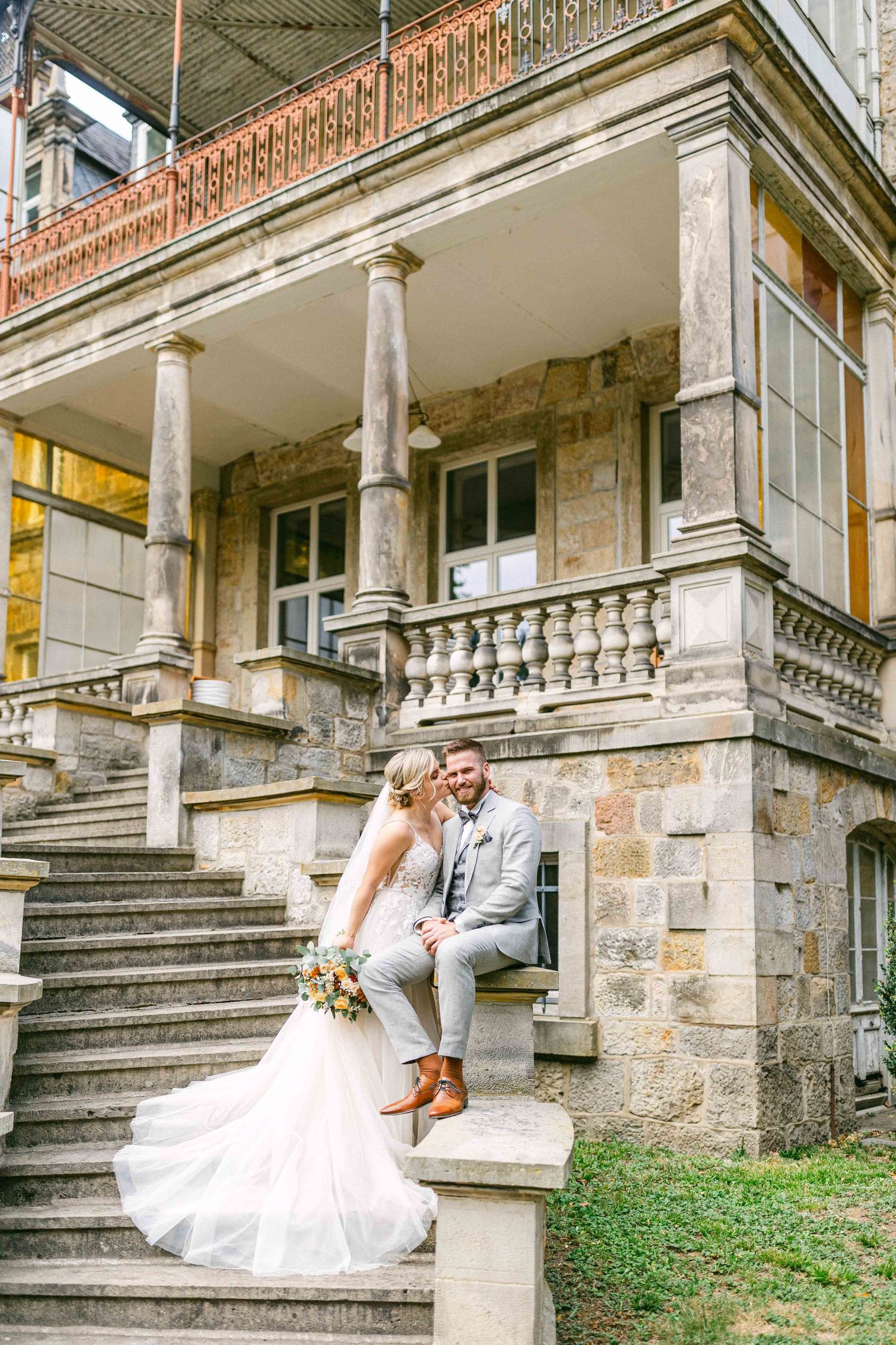 Süßes Foto eines Hochzeitspaares auf den Treppen im Rittergut Voldagsen - fotografiert vom Hochzeitsfotograf Hannover Boris Bounine