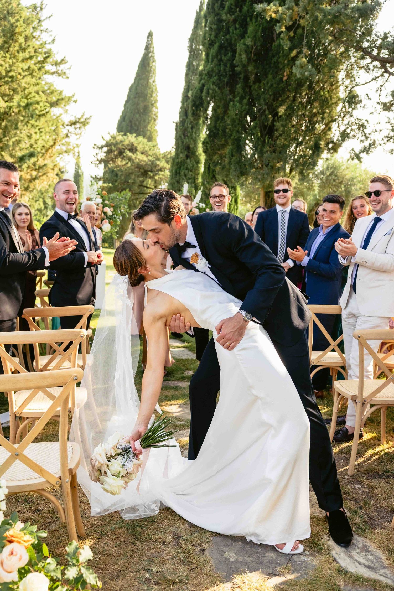 Küssendes Brautpaar bei Ihrer freien Trauung in der Toskana mit Gästen - aufgenommen vom Hochzeitsfotograf aus Hannover