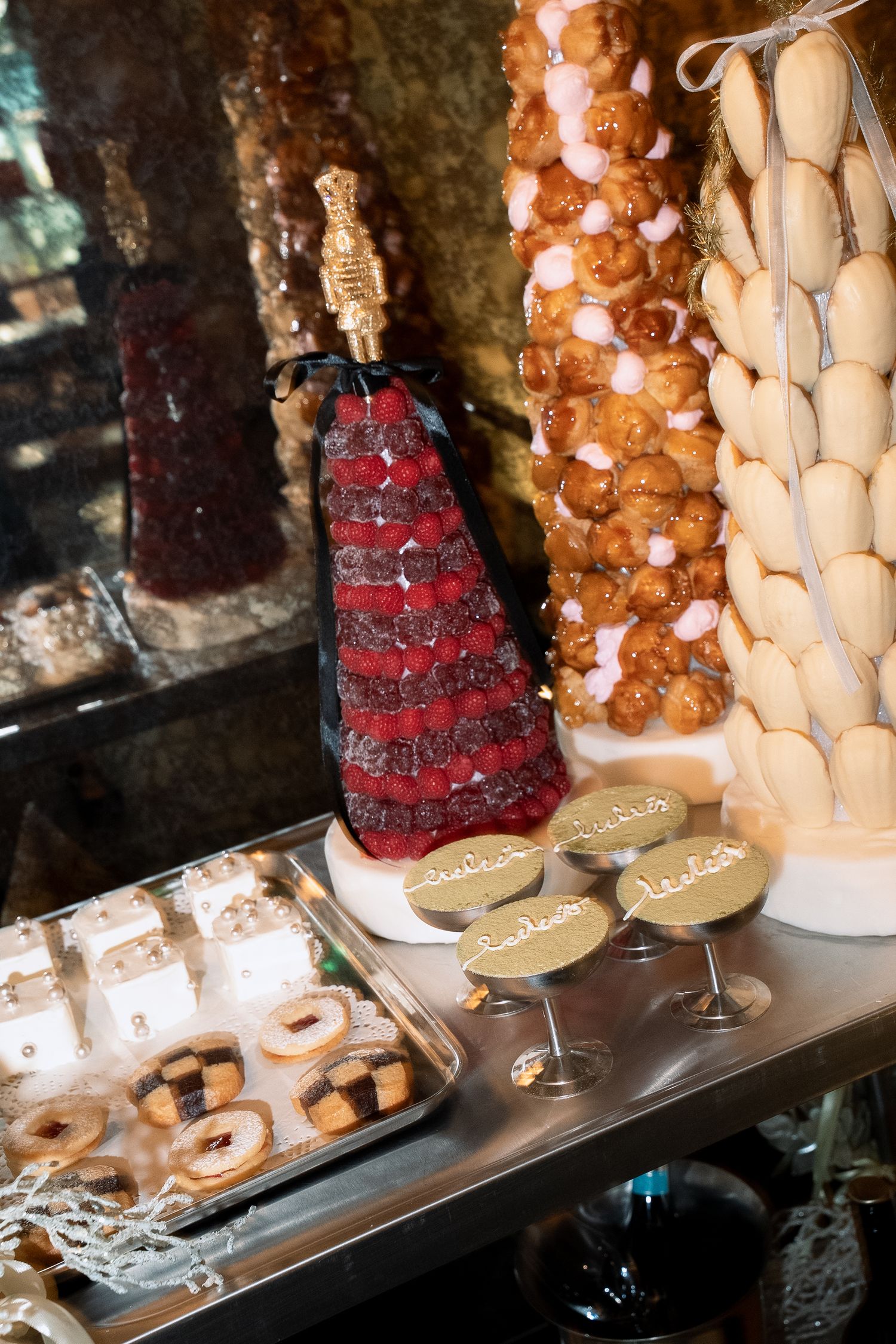 Elegant wedding dessert table featuring croquembouche, macarons, donuts, and decorative sweet displays.