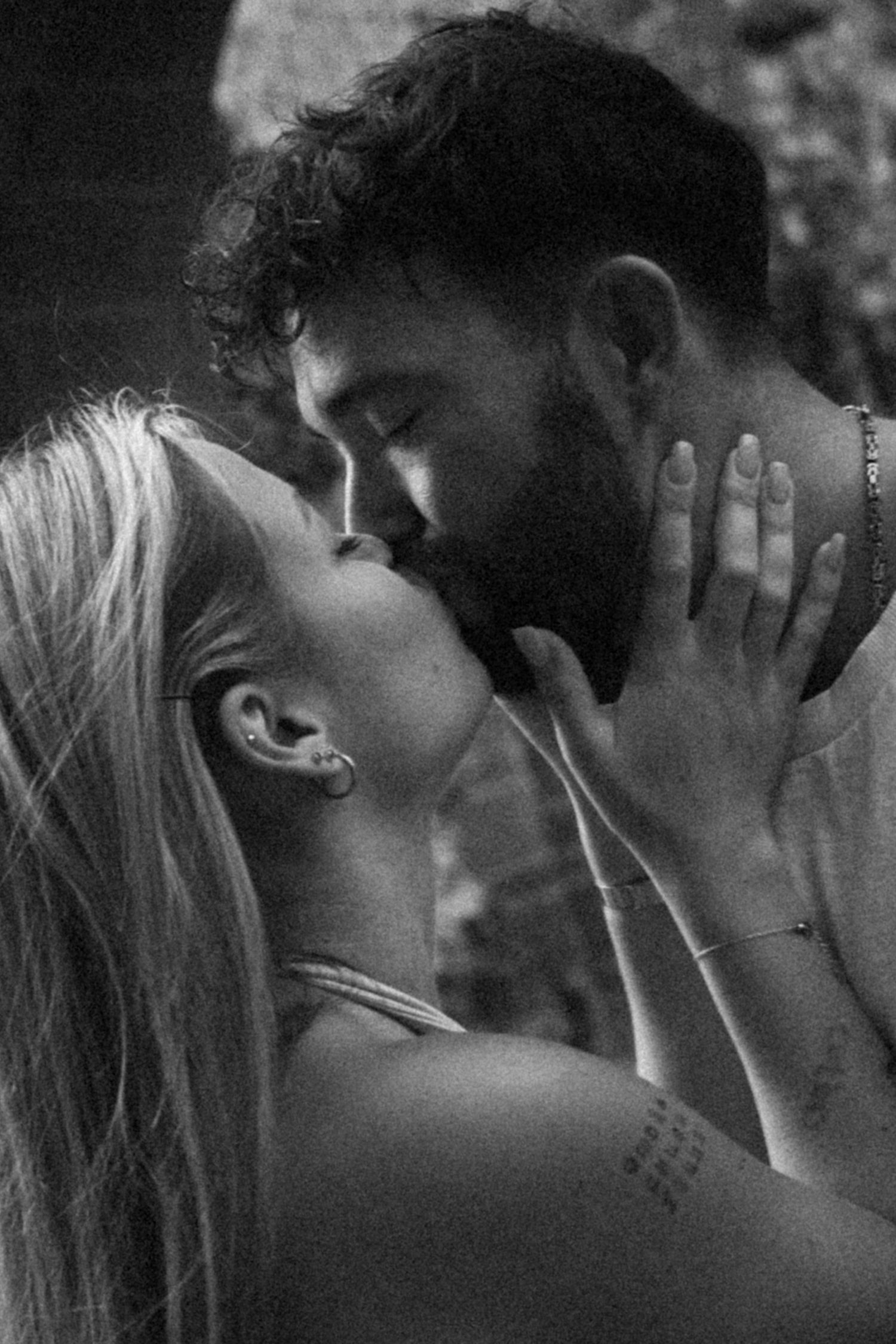 Black and white intimate close-up of a couple about to kiss, woman's hand gently touching man's bearded face.