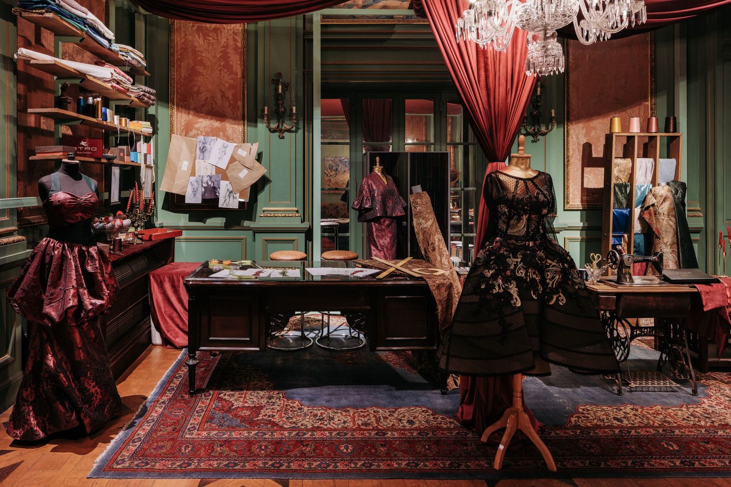 Luxury fashion design studio with vintage gowns, sewing machine, Persian rug, and red velvet drapes.