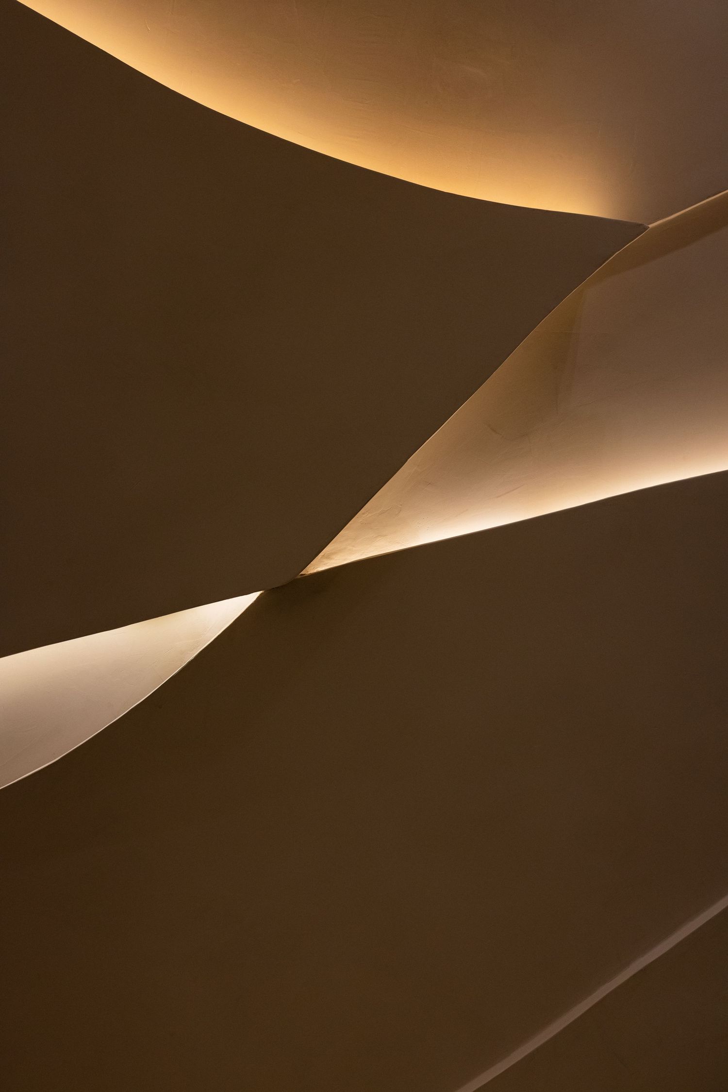 Abstract architectural detail of curved warm-toned walls with glowing LED strip lighting accents.