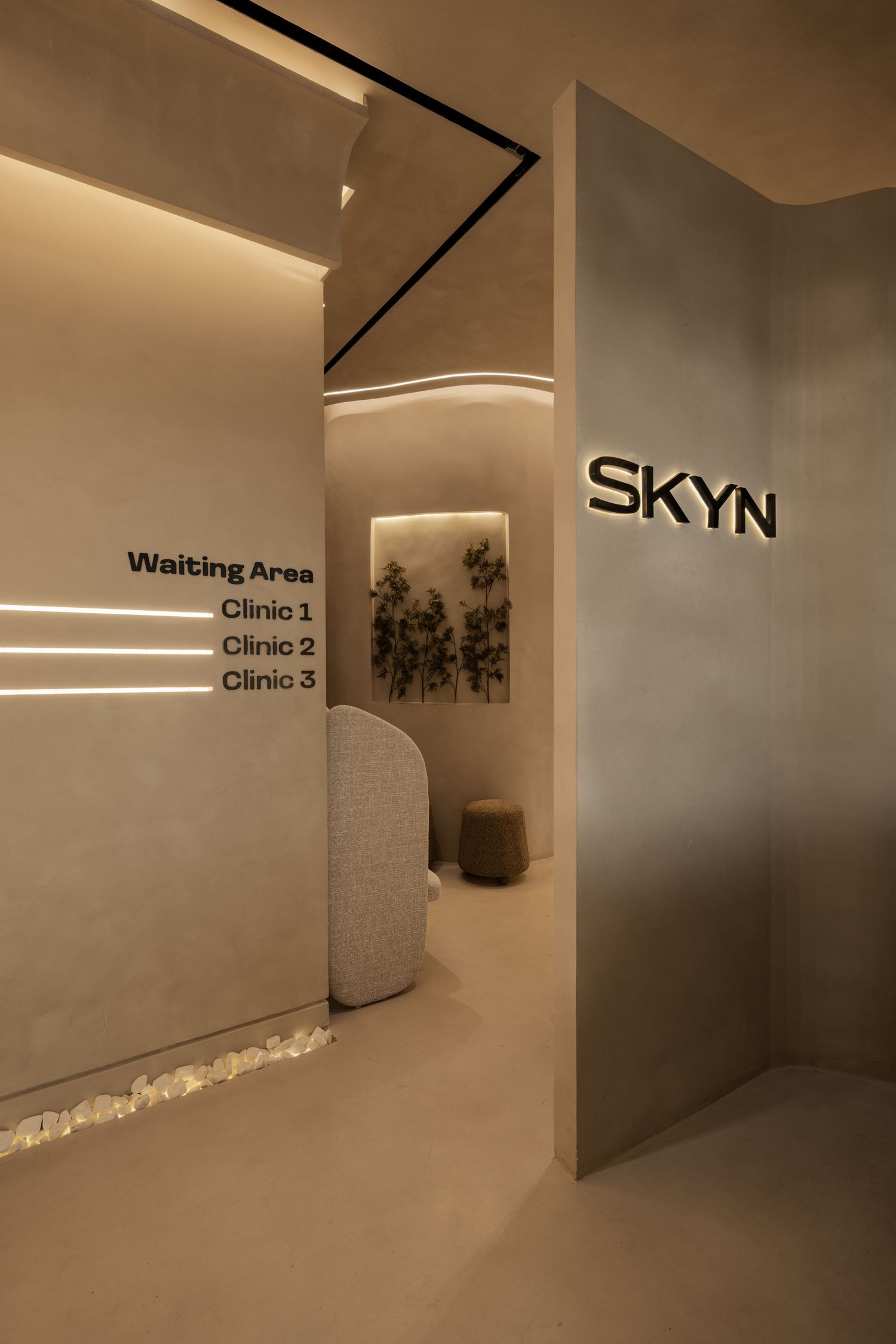 Modern SKYN clinic entrance with warm lighting, directional signage for waiting area and three clinic rooms.