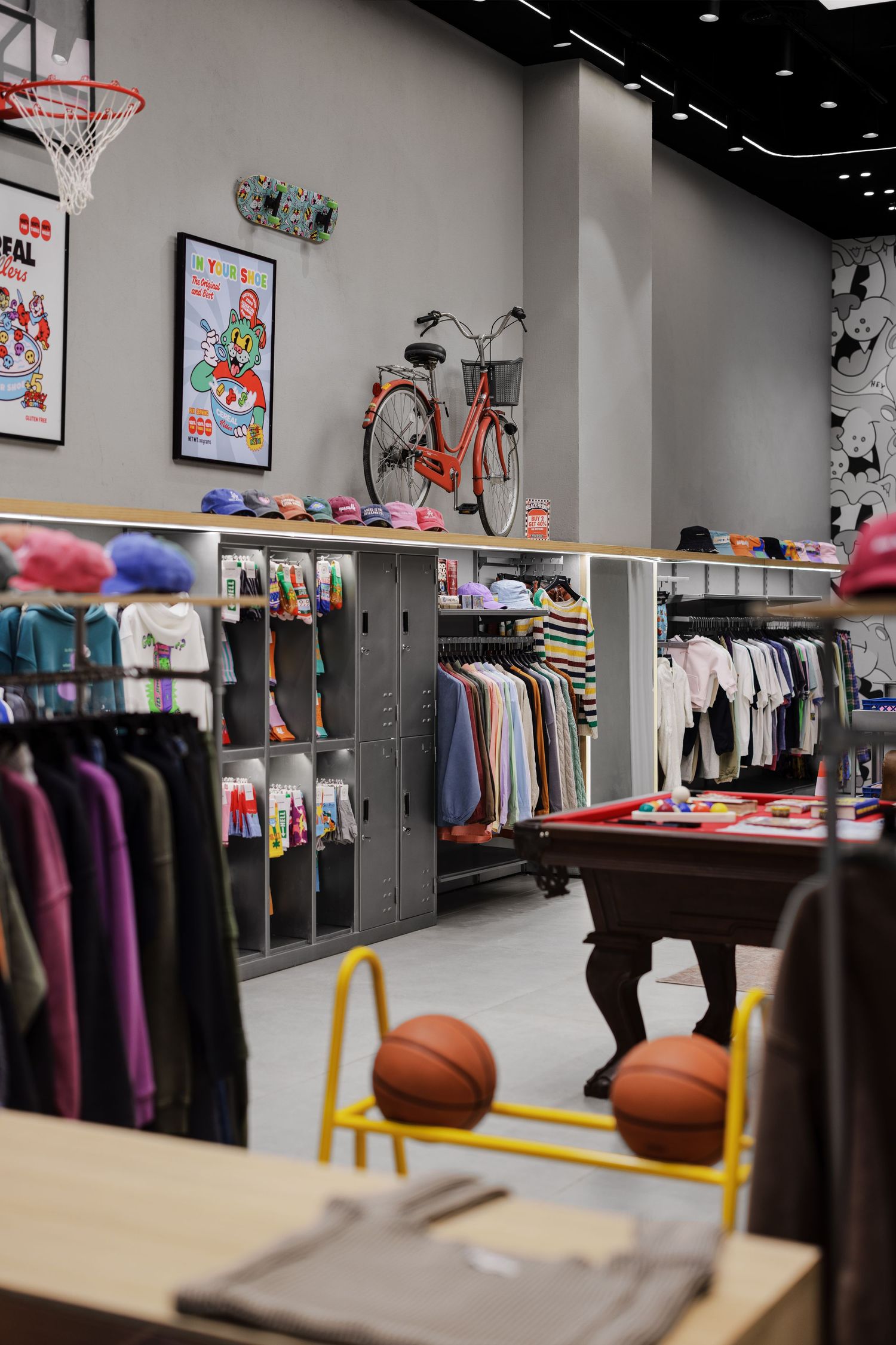 Vibrant kids retail store with colorful clothing racks, basketball, bicycle wall decor, and skate art.