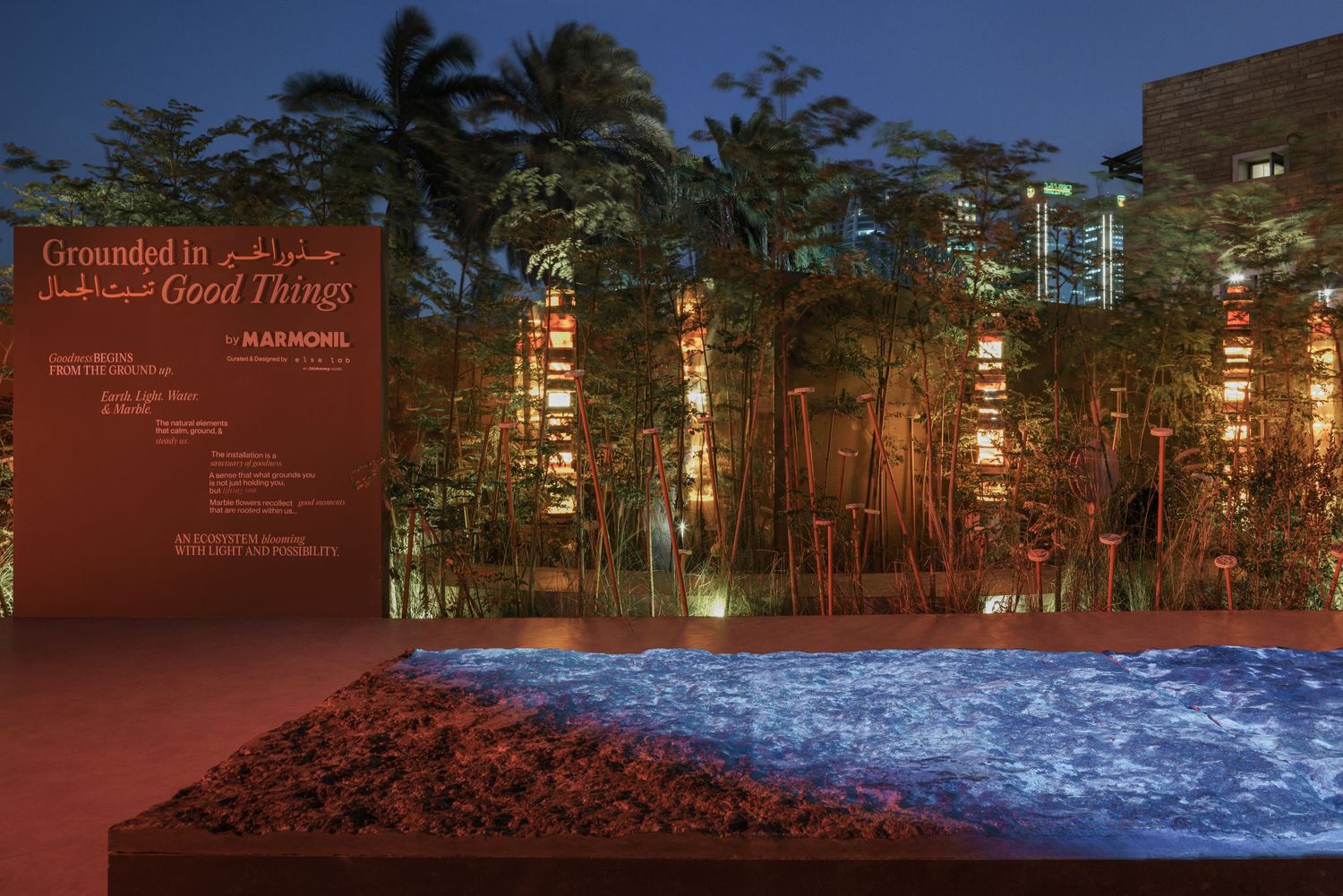 Grounded in Good Things by Marimekko outdoor exhibit with blue sand art and illuminated bamboo at night.