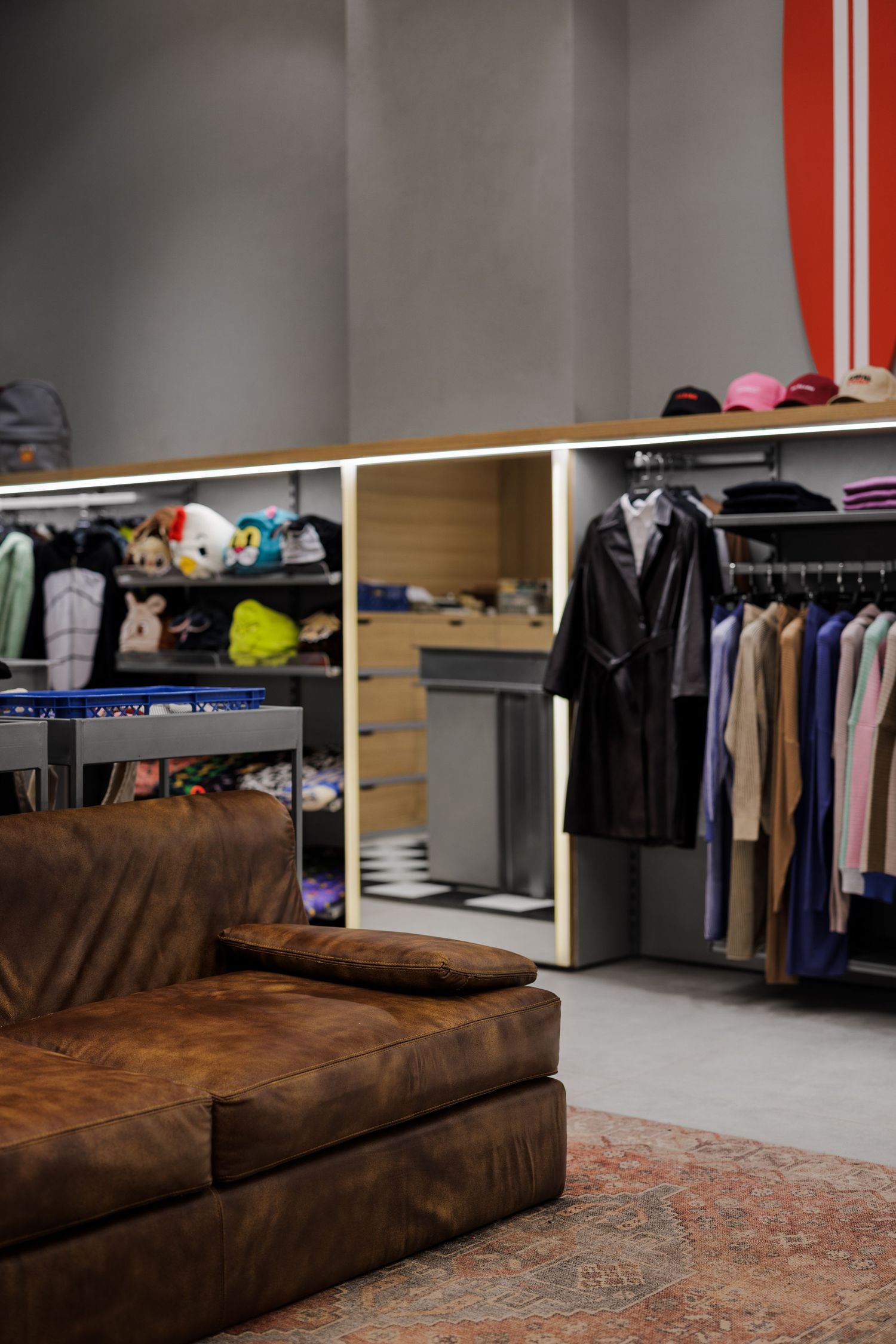 Boutique clothing store interior with leather sofa, apparel racks, and toy displays.