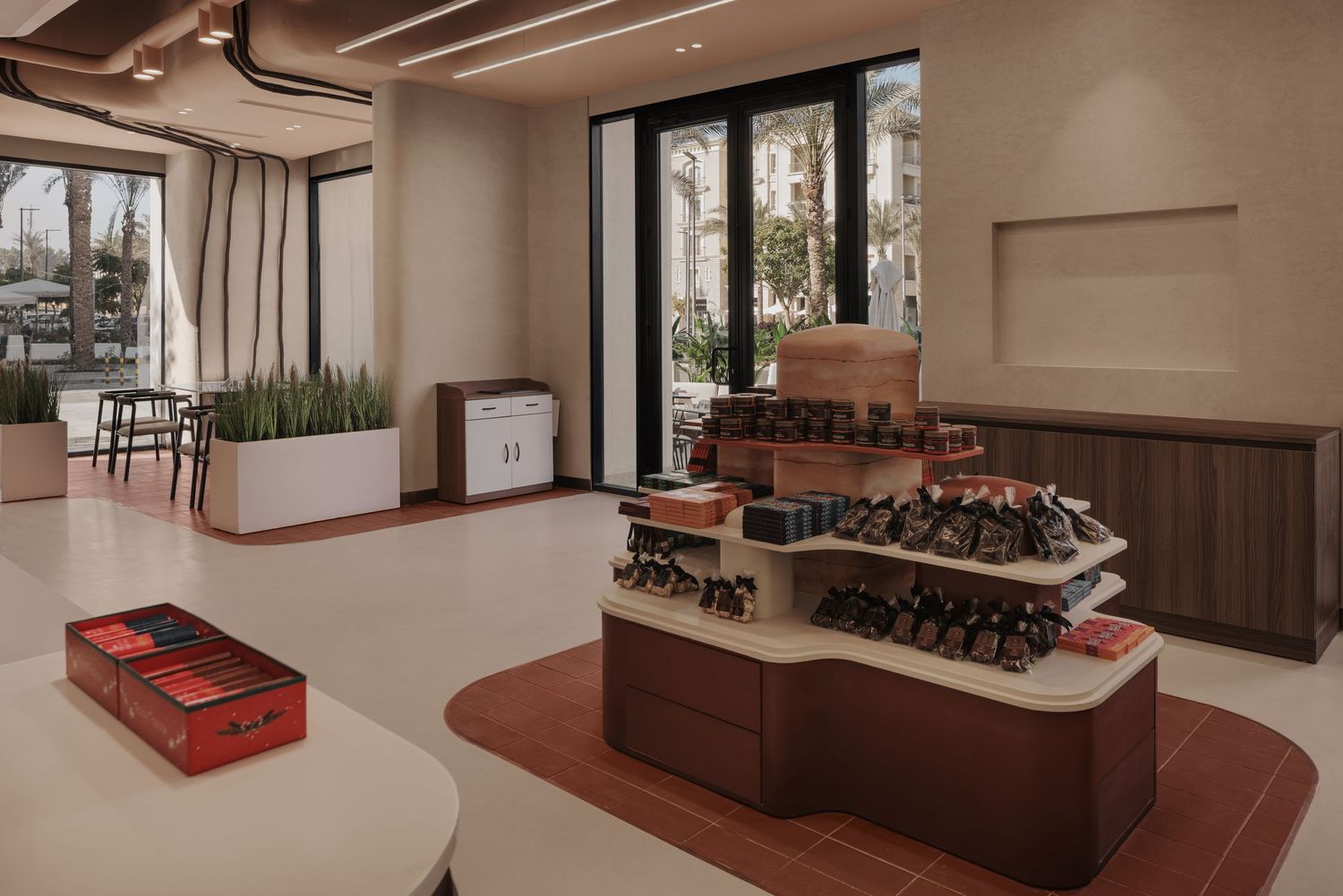 Modern retail interior with tiered wooden display stand showcasing products near large street-view windows.