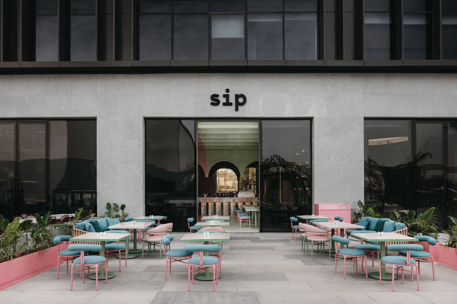 Sip cafe exterior with pastel pink and teal outdoor seating arranged on a modern urban patio.