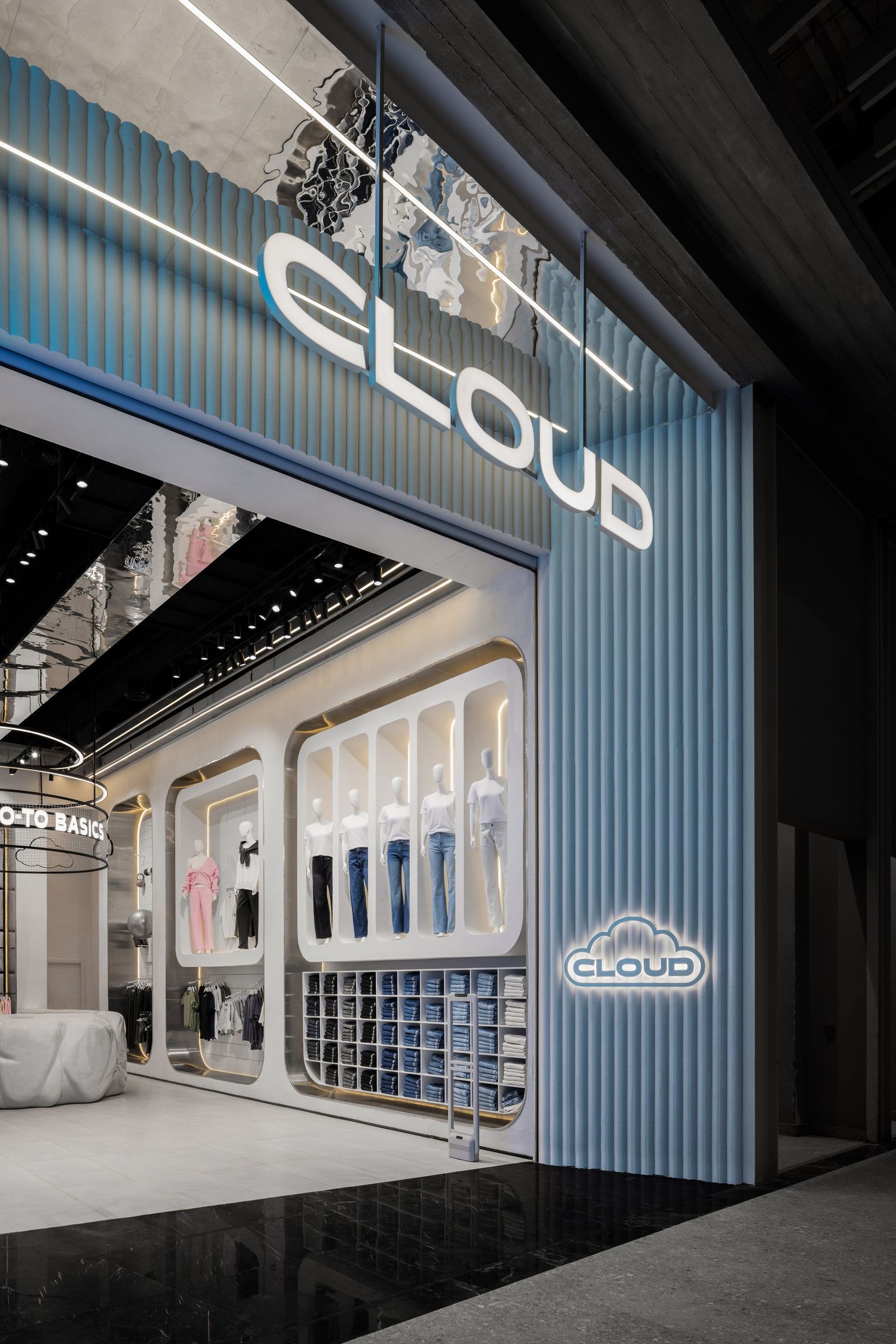 CLOUD retail store exterior with light blue ribbed facade, illuminated signage, and clothing window displays.