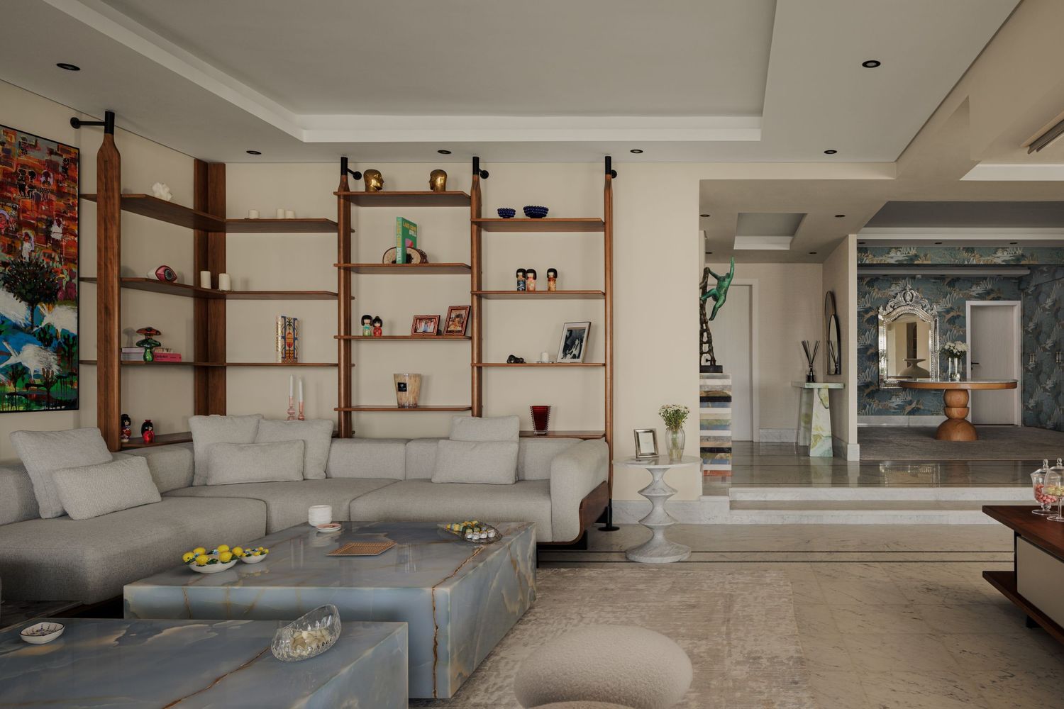 Spacious modern living room with gray sectional sofa, wooden shelving wall unit, and vibrant large-scale artwork.