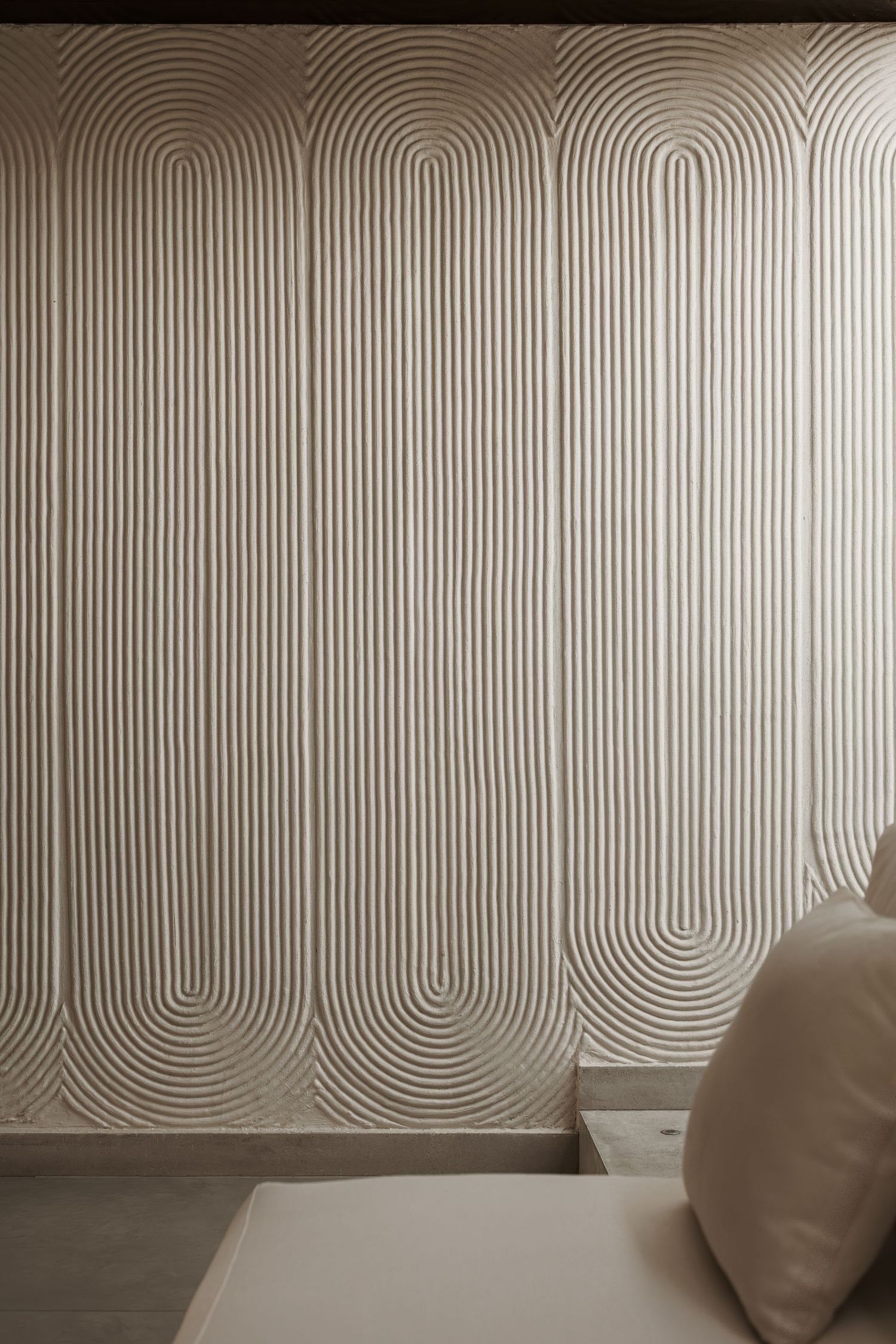 Textured beige wall panel featuring repeating raised arch line patterns in a minimalist interior design.