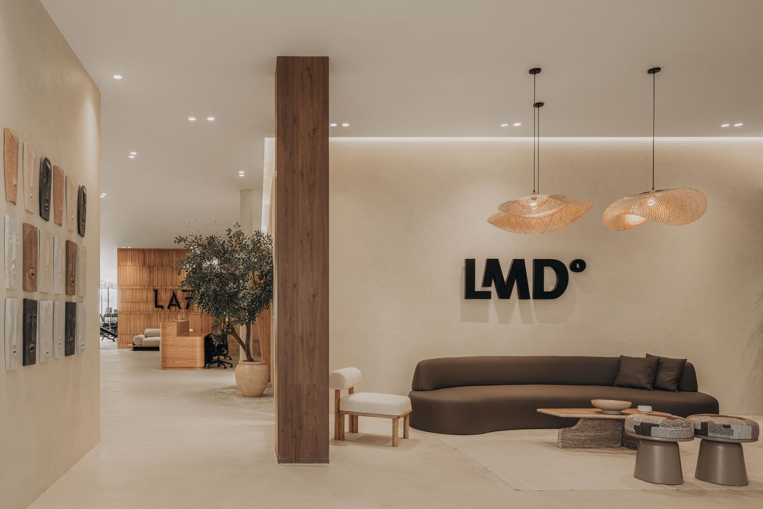Elegant LMD wellness center lobby with warm lighting, rattan pendants, curved sofa, and natural wood accents.