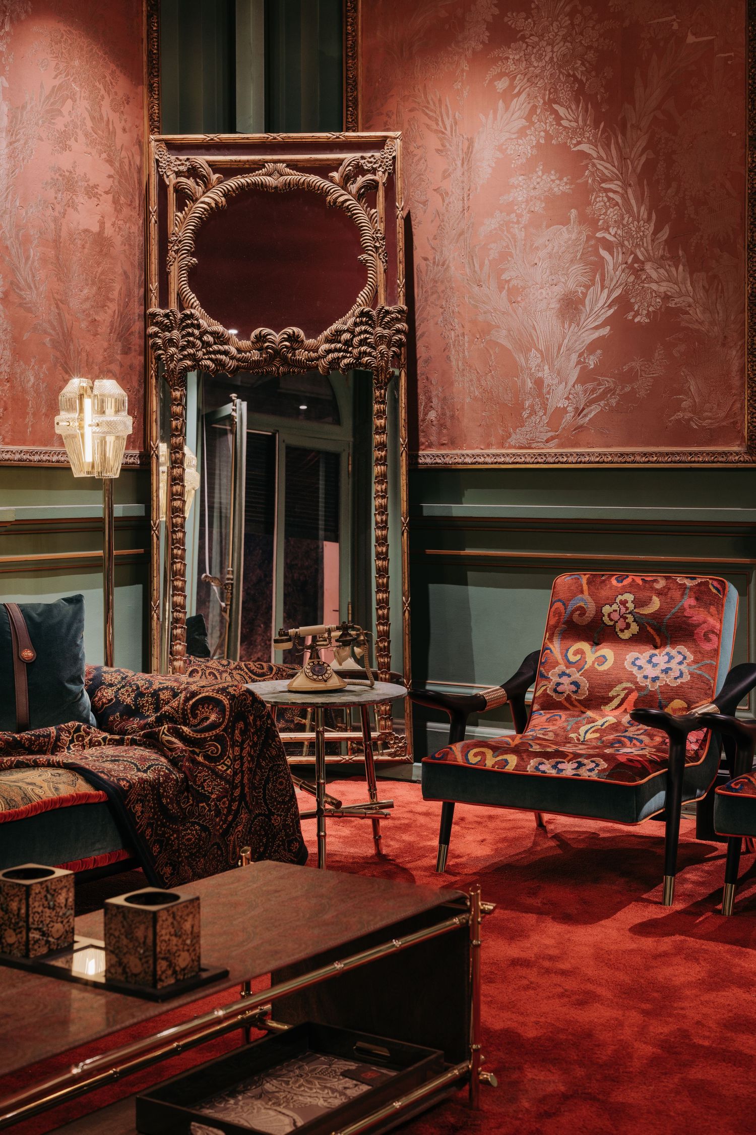 Opulent red room with ornate gilded mirror, patterned armchairs, and decorative wall finish in vintage interior.