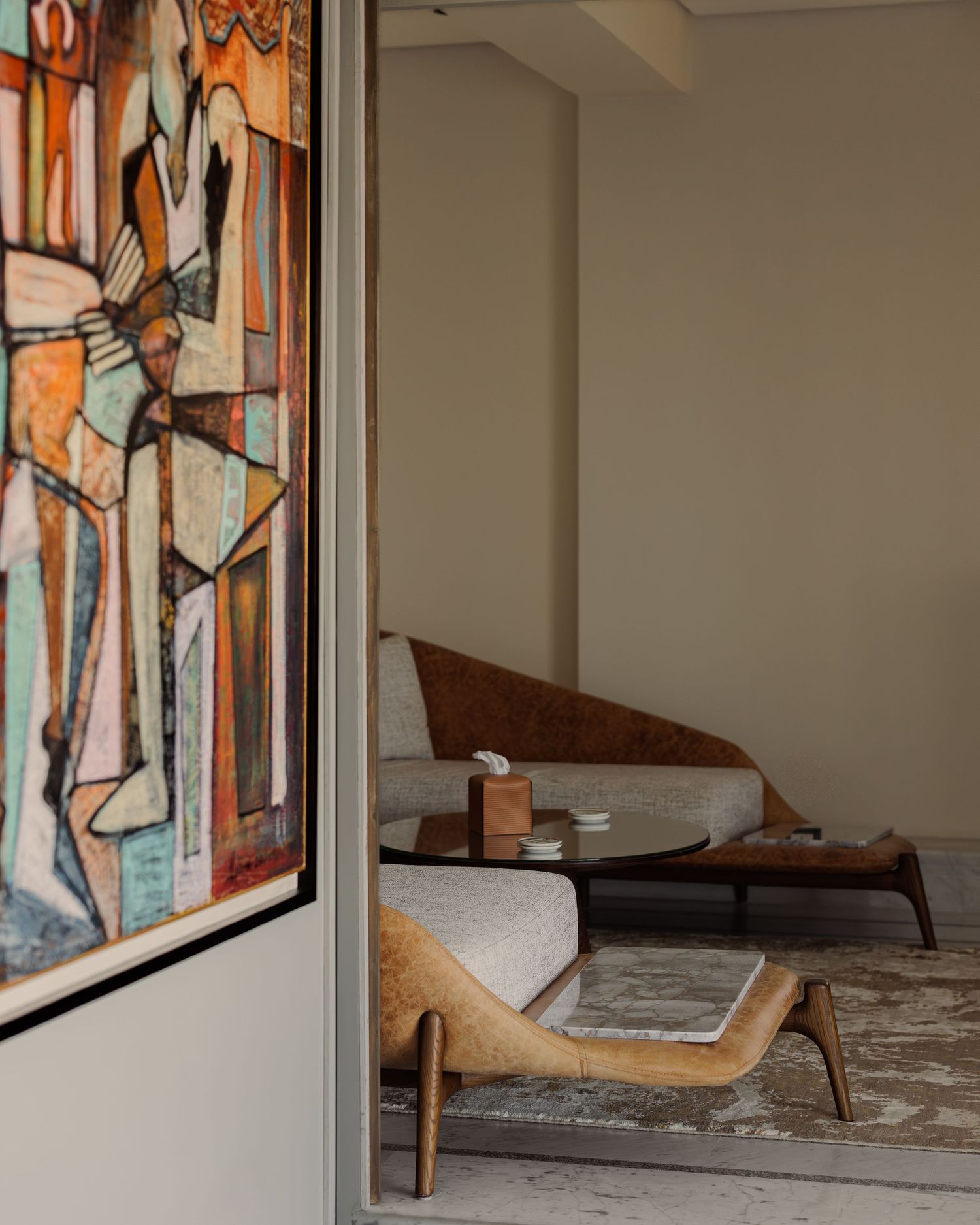 Elegant living room with abstract cubist artwork, curved wooden sofa, and minimalist decor in warm neutral tones.