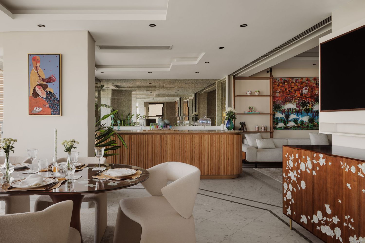 Spacious open-plan living and dining area with wooden island, floral credenza, colorful artwork, and elegant neutral furnishings.