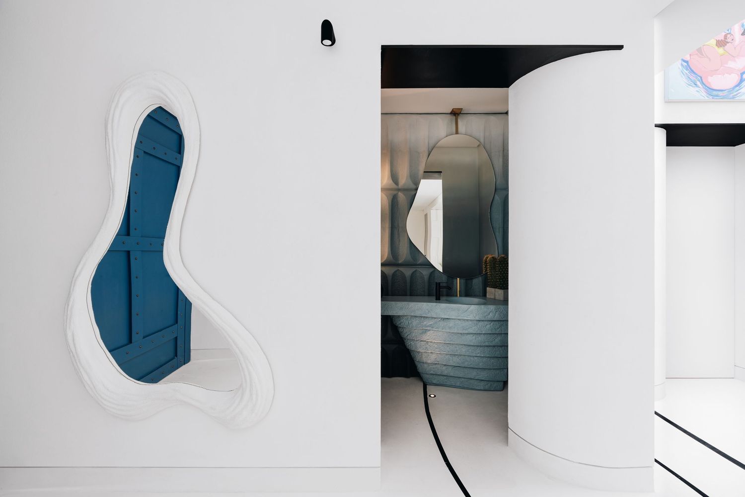 Modern white interior with organic blue wall art panel and curved doorway leading to a stylish bathroom.