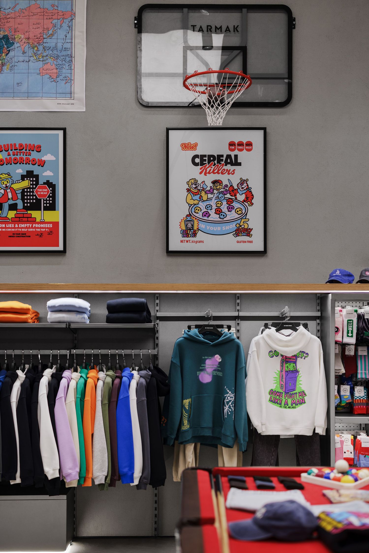 Streetwear store display with hoodies, basketball hoop, and Cereal Killers poster.