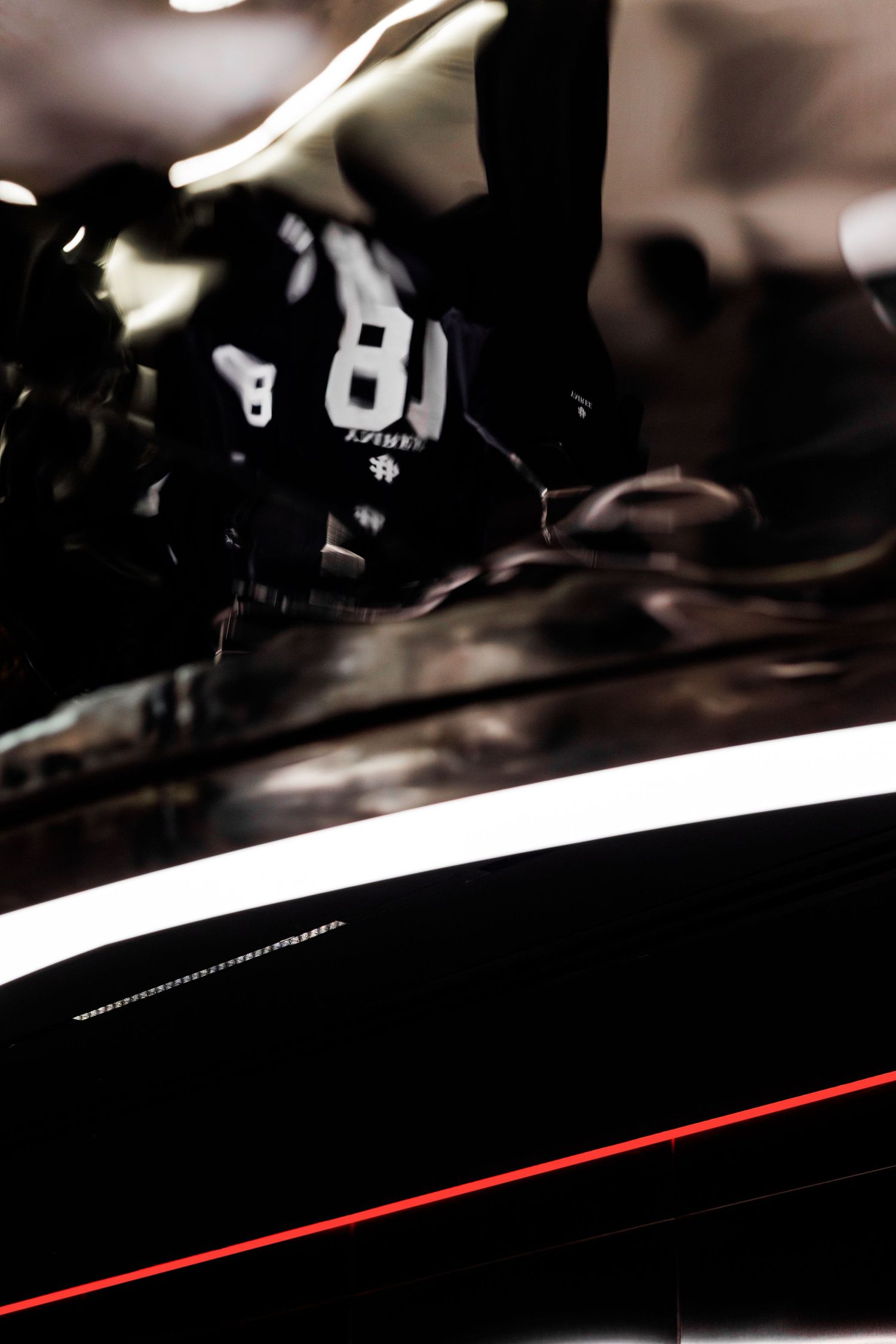 Close-up of glossy black surface with white and red light stripe reflection.