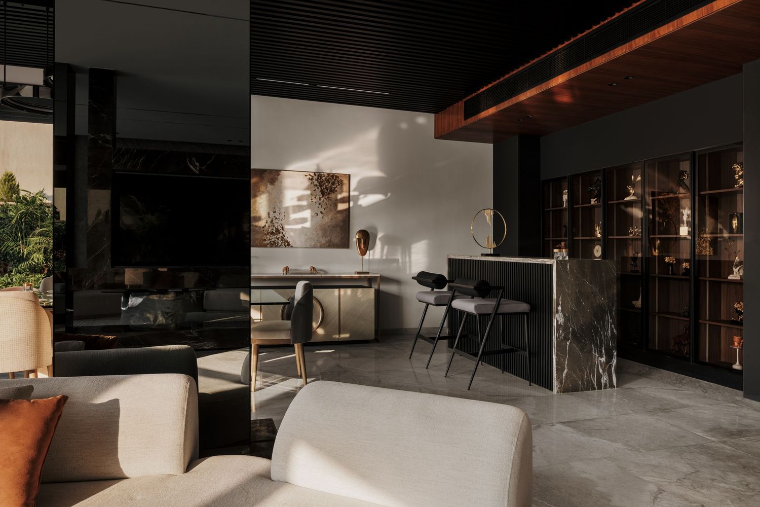 Dark sophisticated interior with marble kitchen island, display cabinetry, and open-plan living and dining zones.