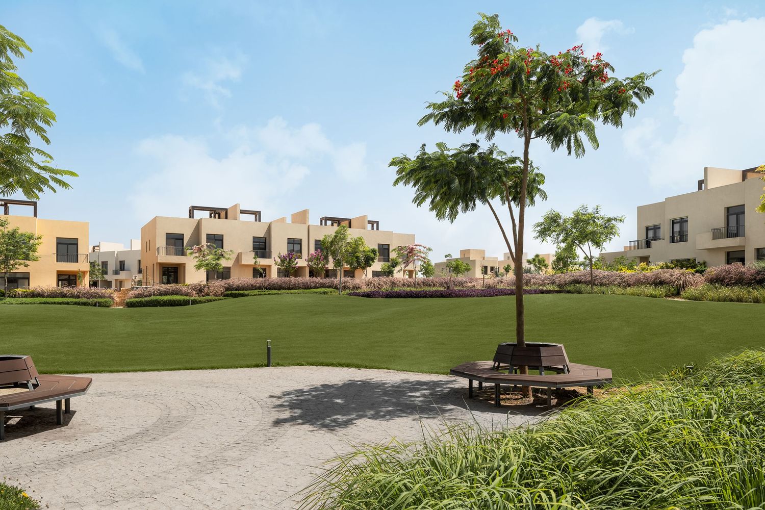 Contemporary townhouses surrounding a spacious green lawn with shaded seating areas and ornamental trees.
