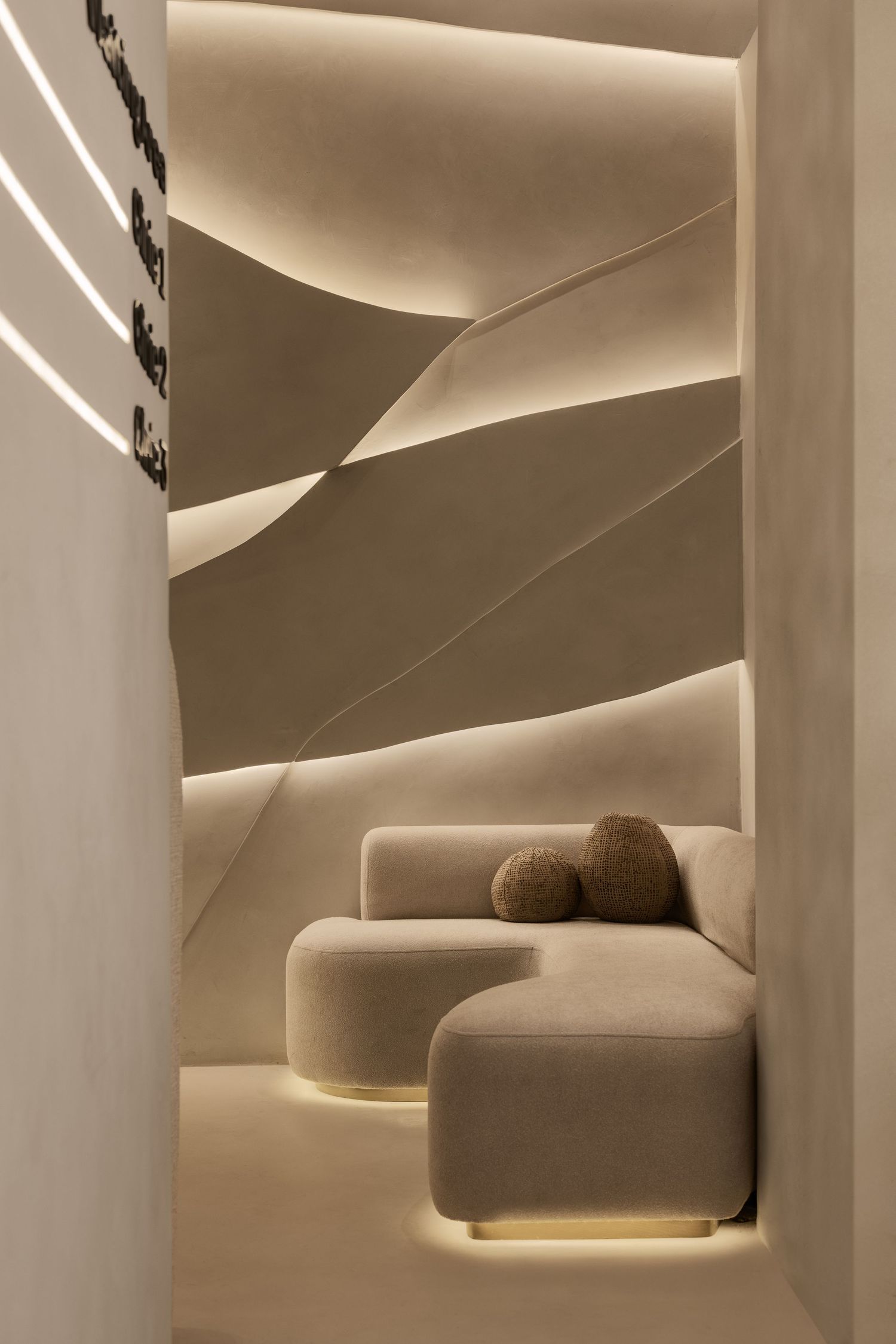 Modern beige interior with sculptural curved walls, LED lighting, and modular velvet sofa seating.