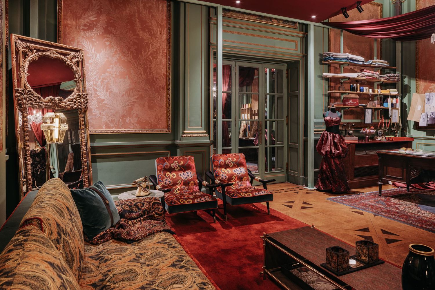 Luxurious vintage room with red carpet, patterned sofa, ornate mirror, green walls, and eclectic decor.