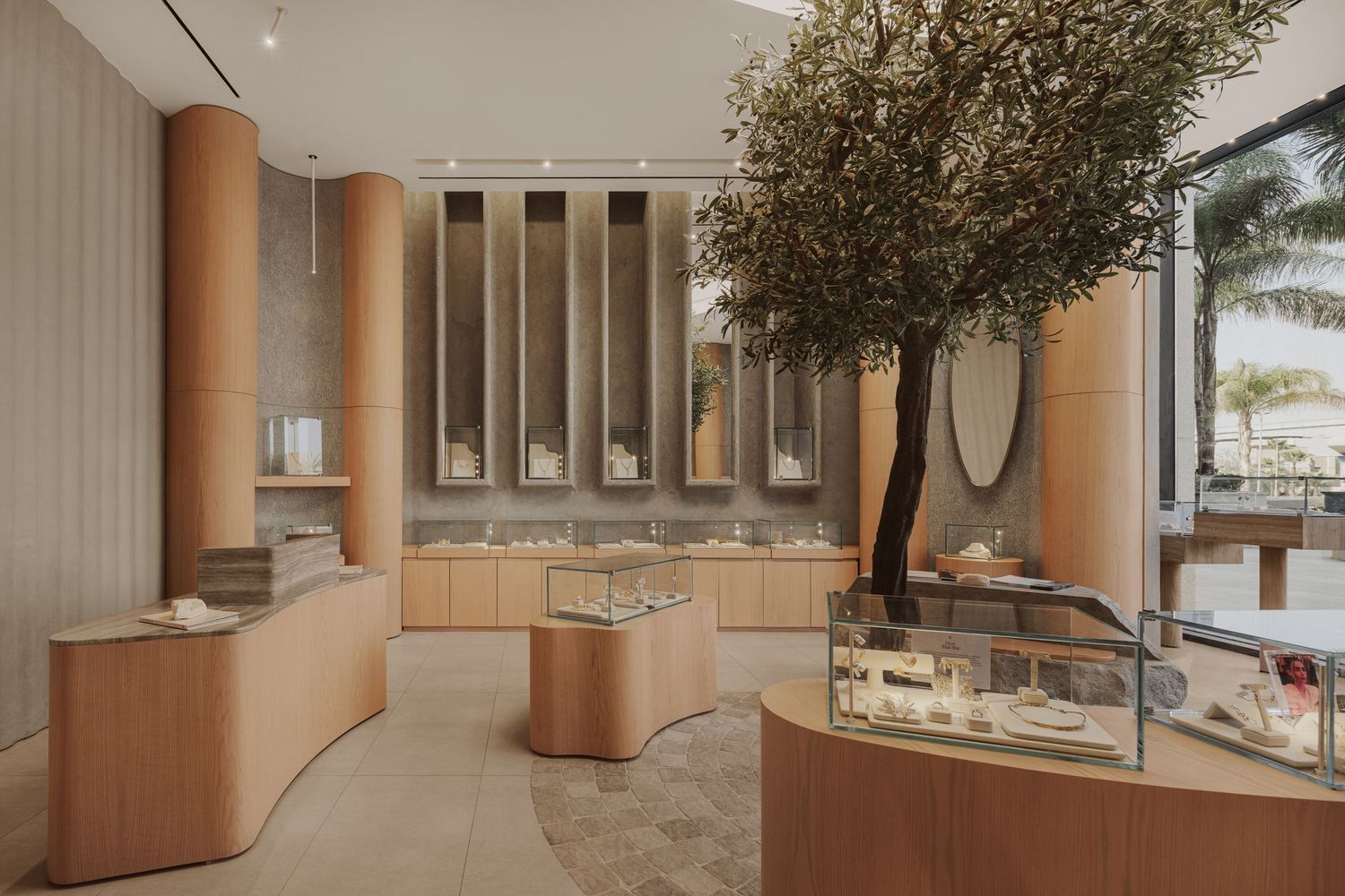 Luxury jewelry store with curved wooden display counters, olive tree centerpiece, and glass showcases.