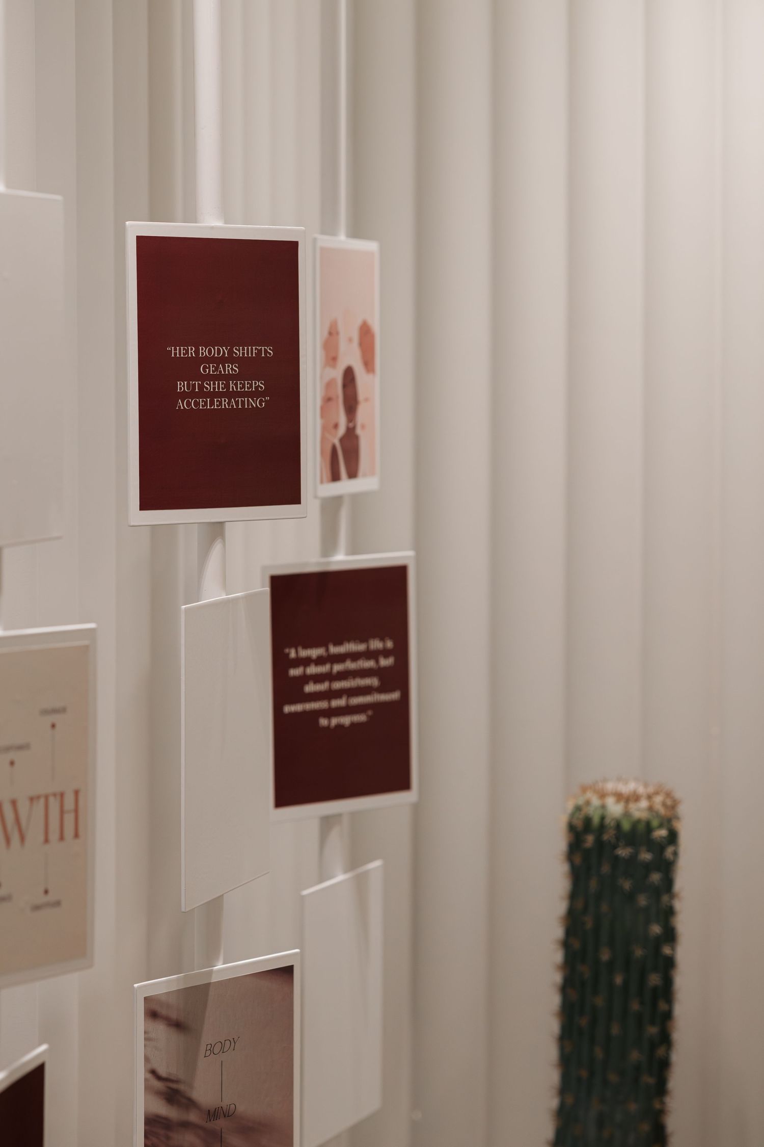 White fluted wall panel display featuring dark red motivational quote cards and health imagery in a modern beauty space.