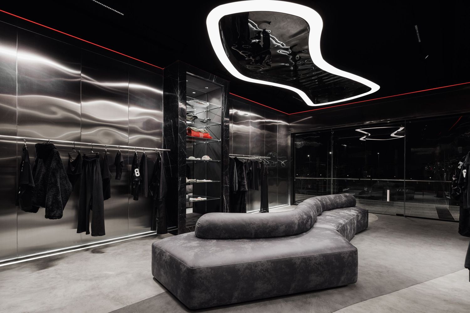 Sleek dark fashion retail space featuring a gray velvet curved sofa, mirrored walls, and dramatic LED ceiling lights.