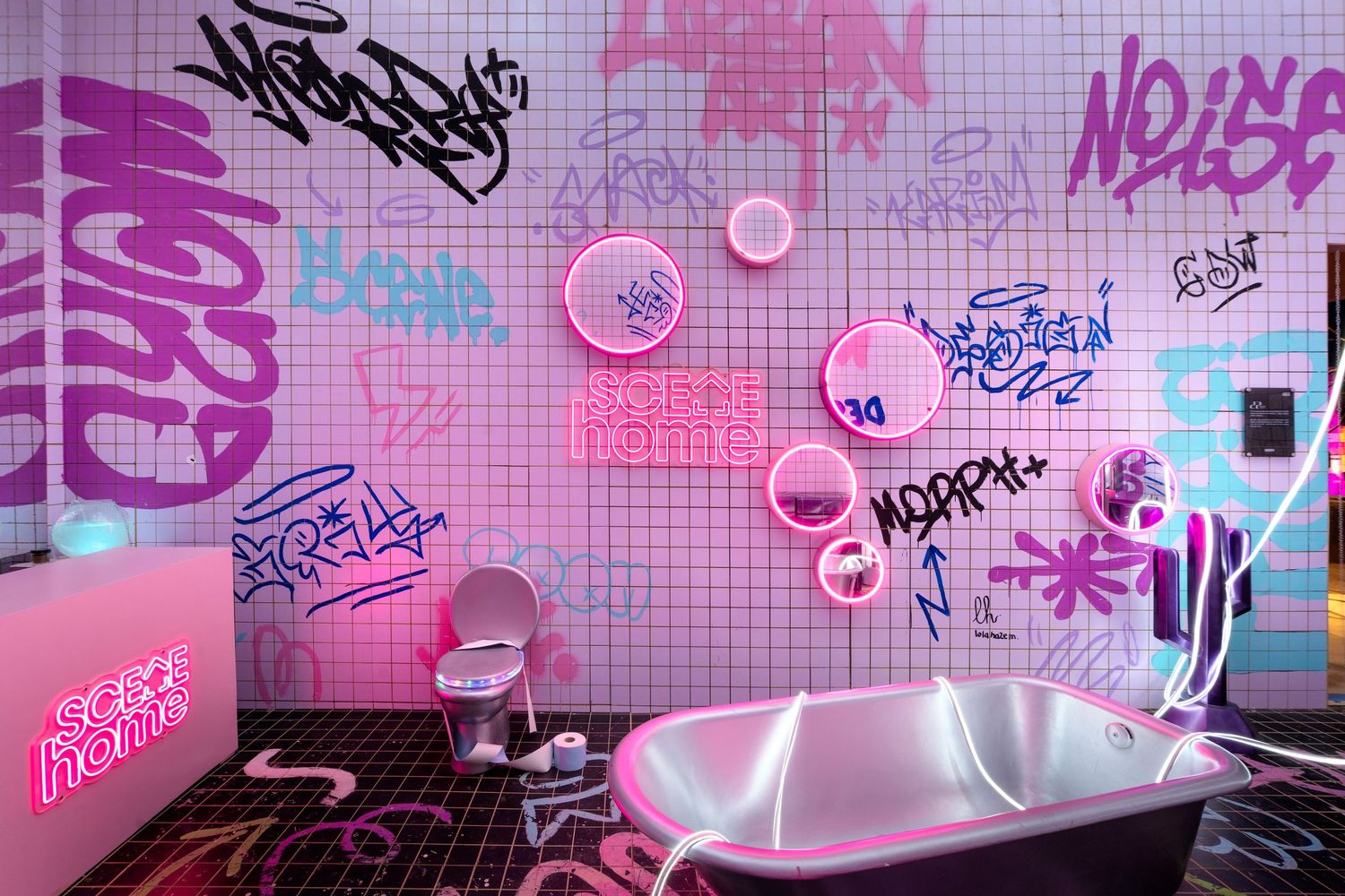 Vibrant pink graffiti bathroom featuring neon signs, freestanding tub, and glowing circle lights.