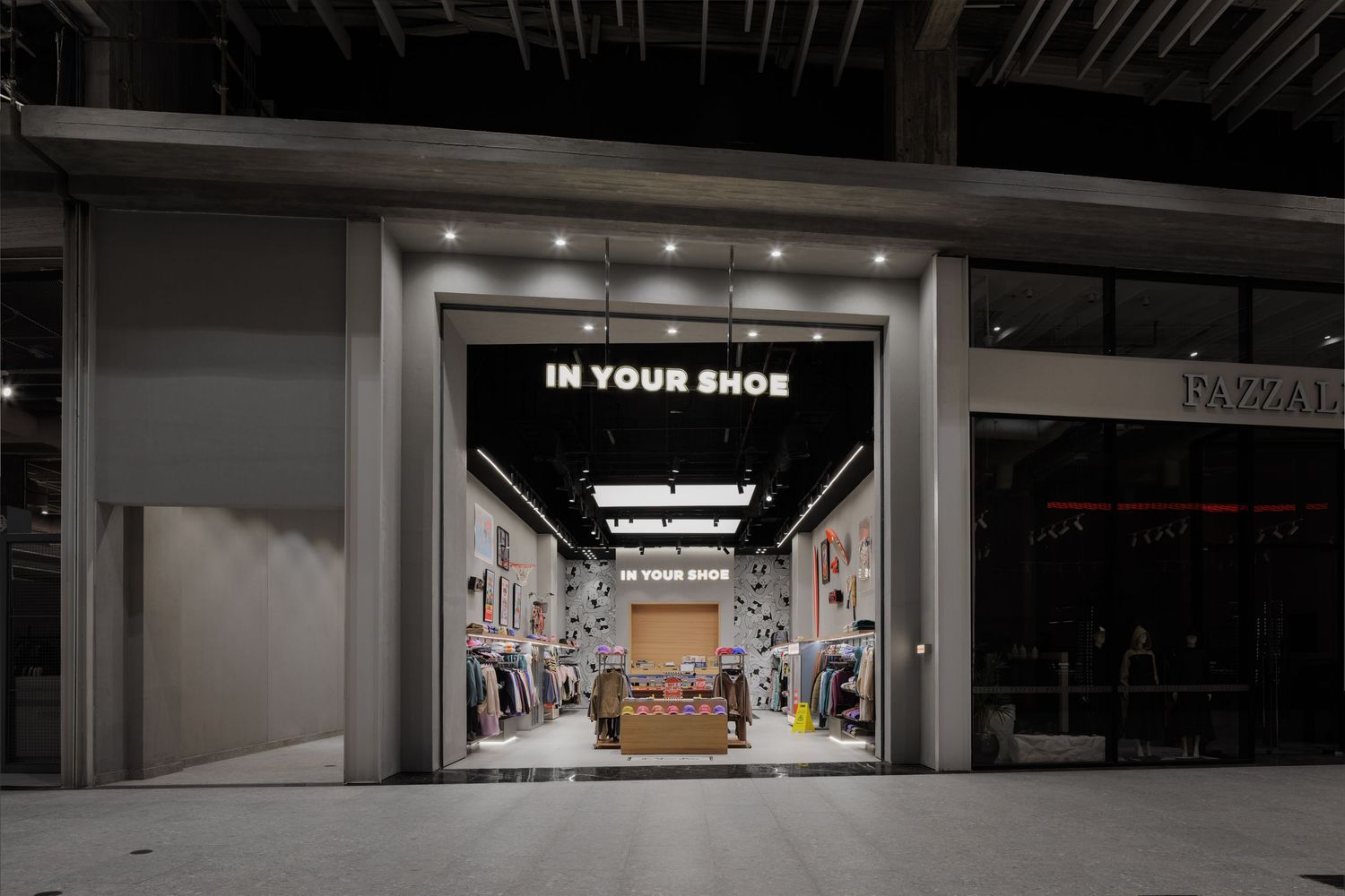 In Your Shoe retail store entrance illuminated at night inside a modern shopping mall.