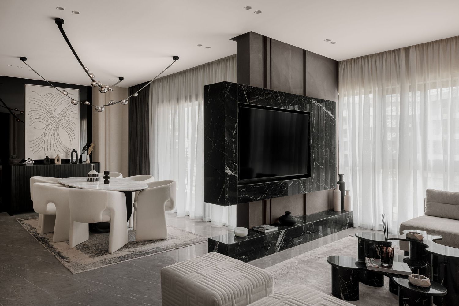 Contemporary open-plan living space with black marble fireplace, white sculptural furniture, and sheer curtains.