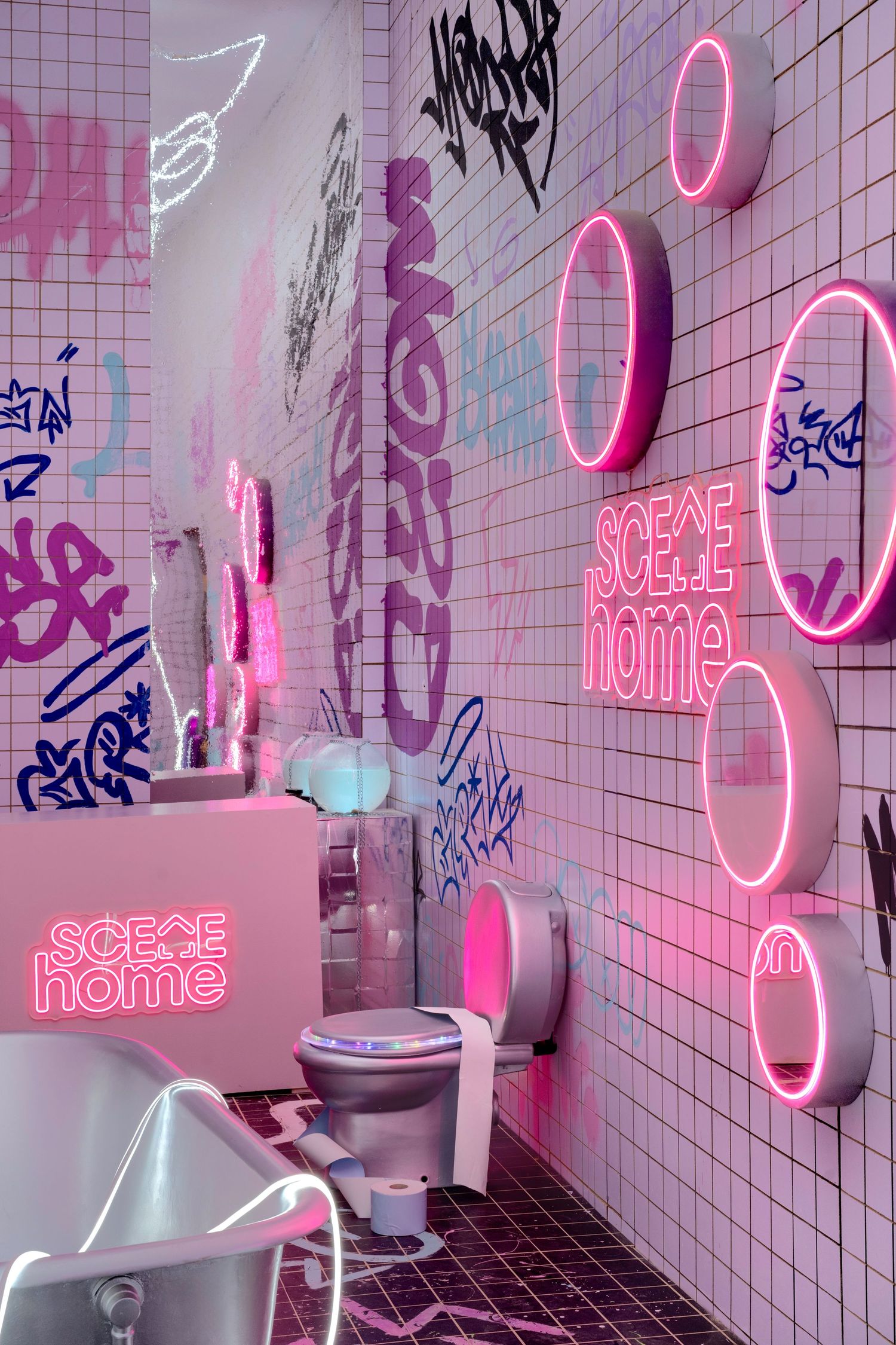 Pink neon bathroom with graffiti walls, circular light fixtures, and Scene Home branding signs.