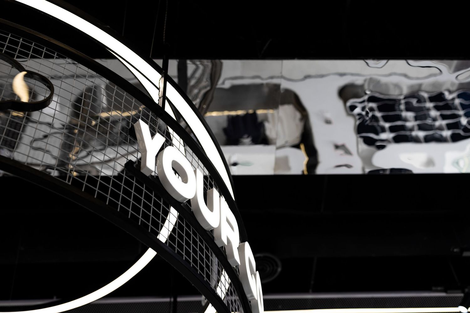 Illuminated circular signage reading YOUR in a dark modern retail store with artistic wall mural backdrop.