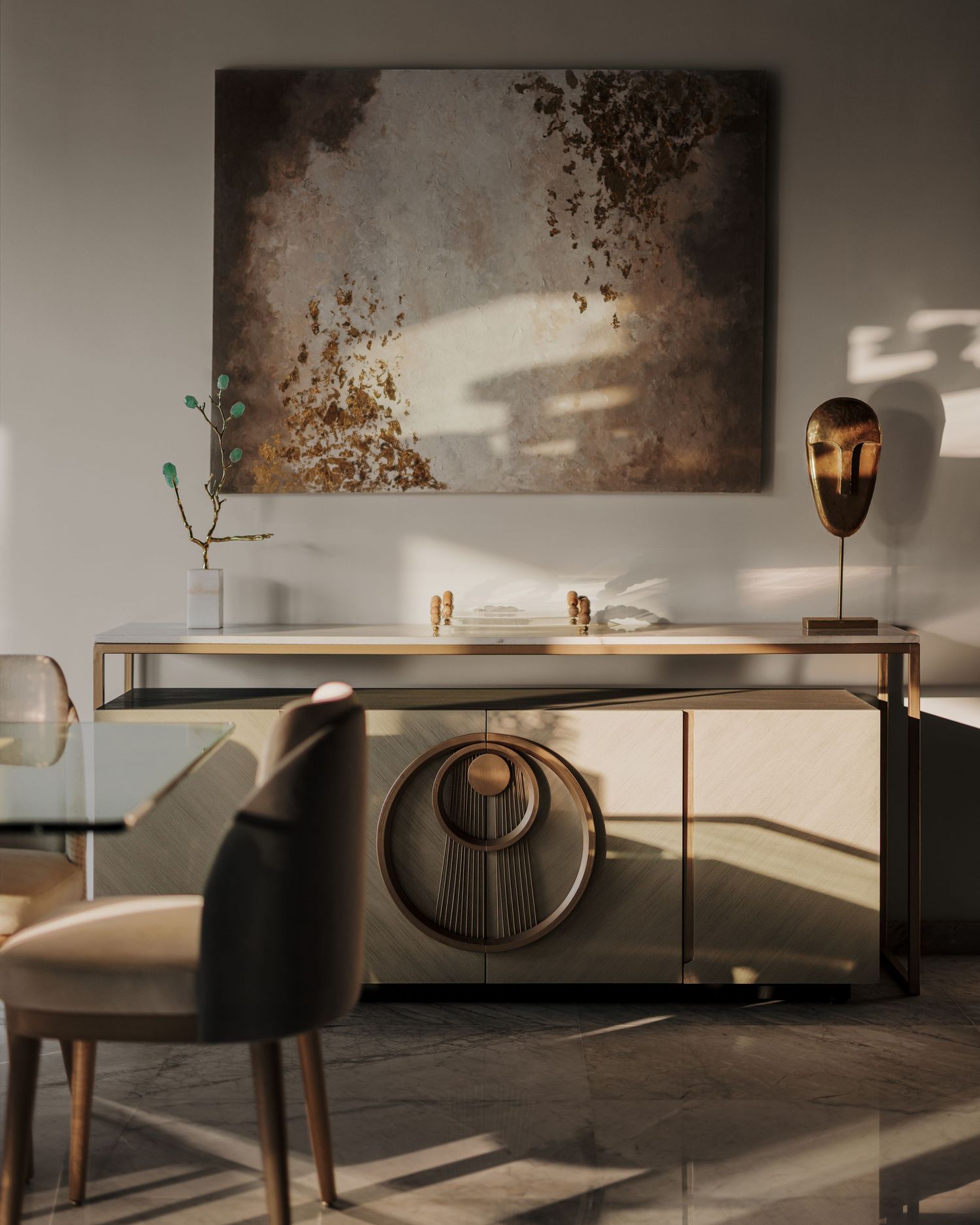 Luxurious gold and bronze sideboard with circular motif beneath large abstract painting, styled with sculptural brass decor accents.