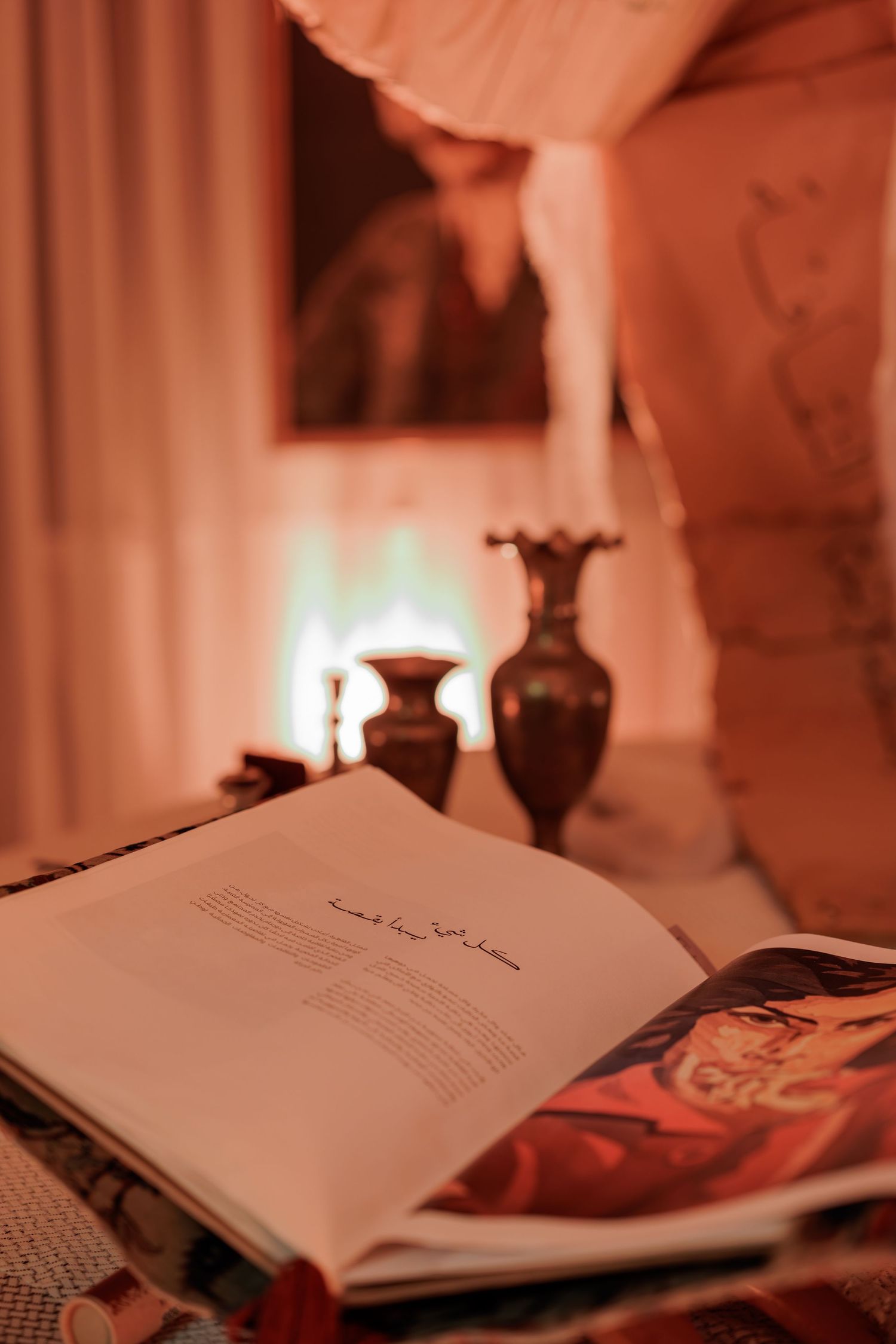 Open book on a table with warm candlelight, decorative vases, and soft glowing ambiance in background.