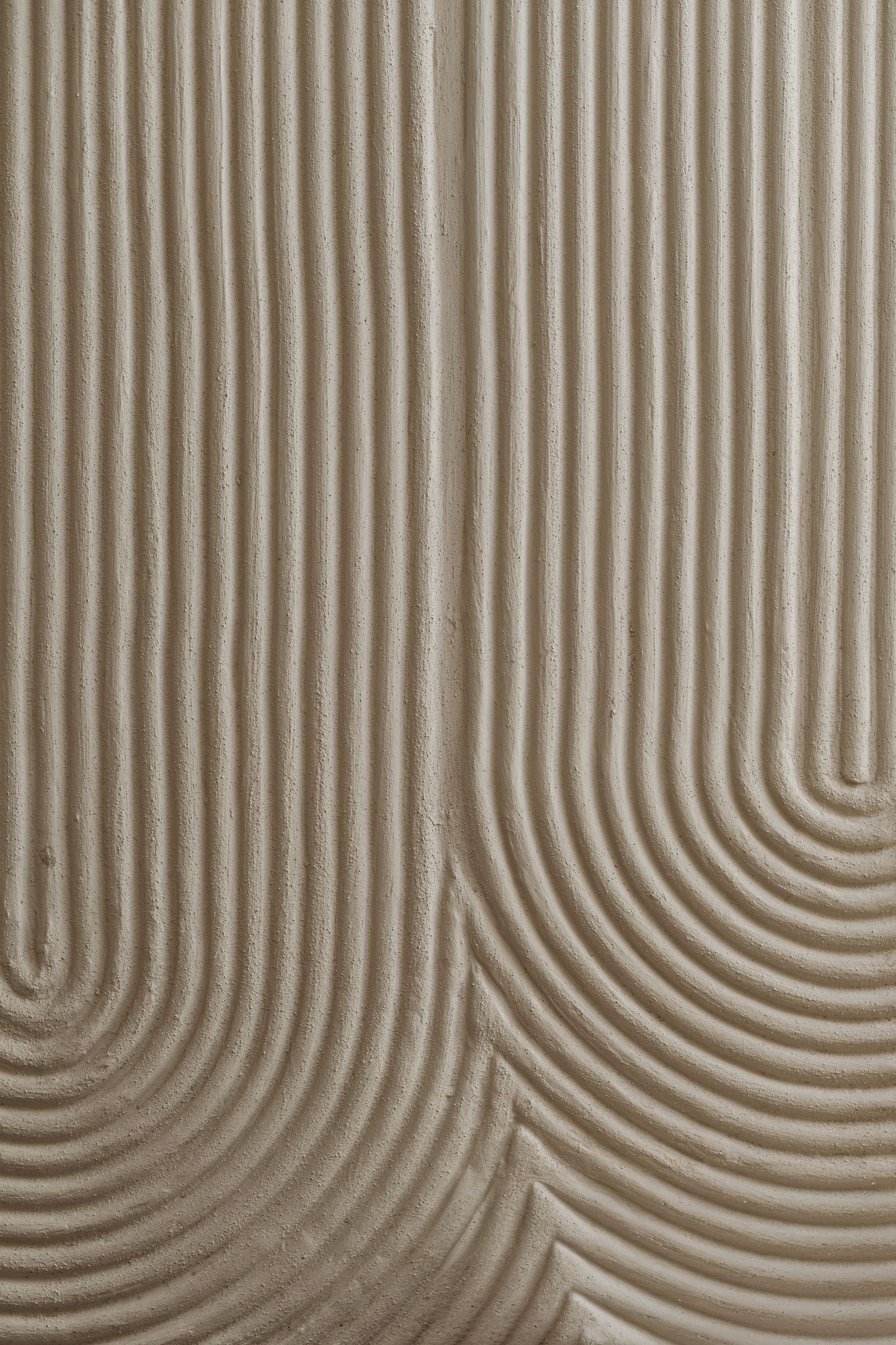 Close-up of a beige textured wall surface with carved concentric arch groove patterns in relief design.