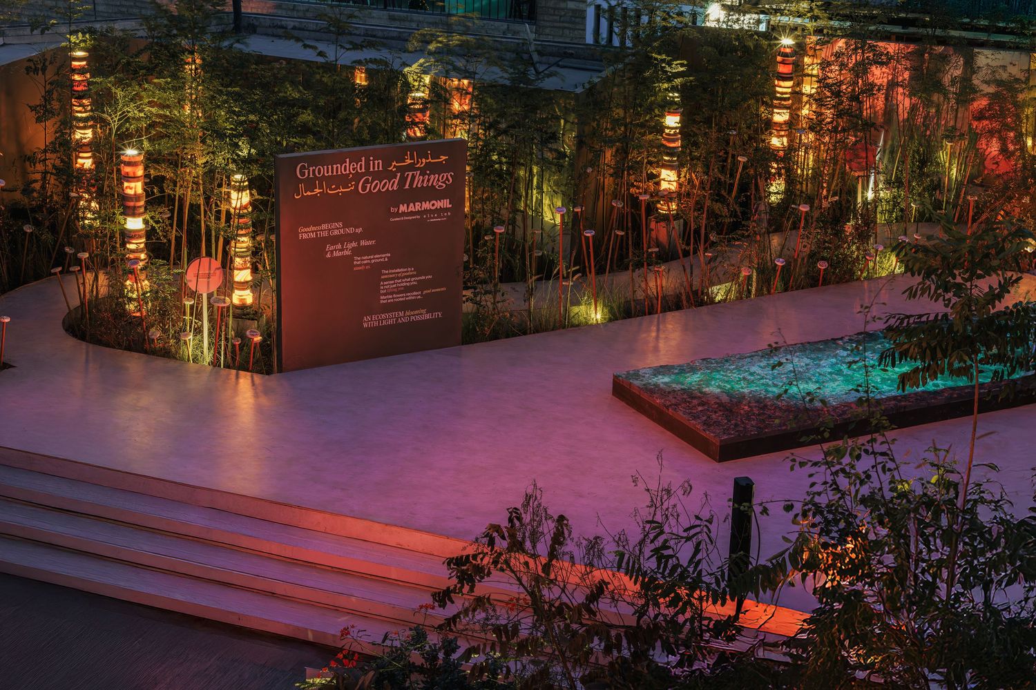 Illuminated outdoor exhibition space with bamboo, glowing lanterns, and a bilingual welcome sign at dusk.