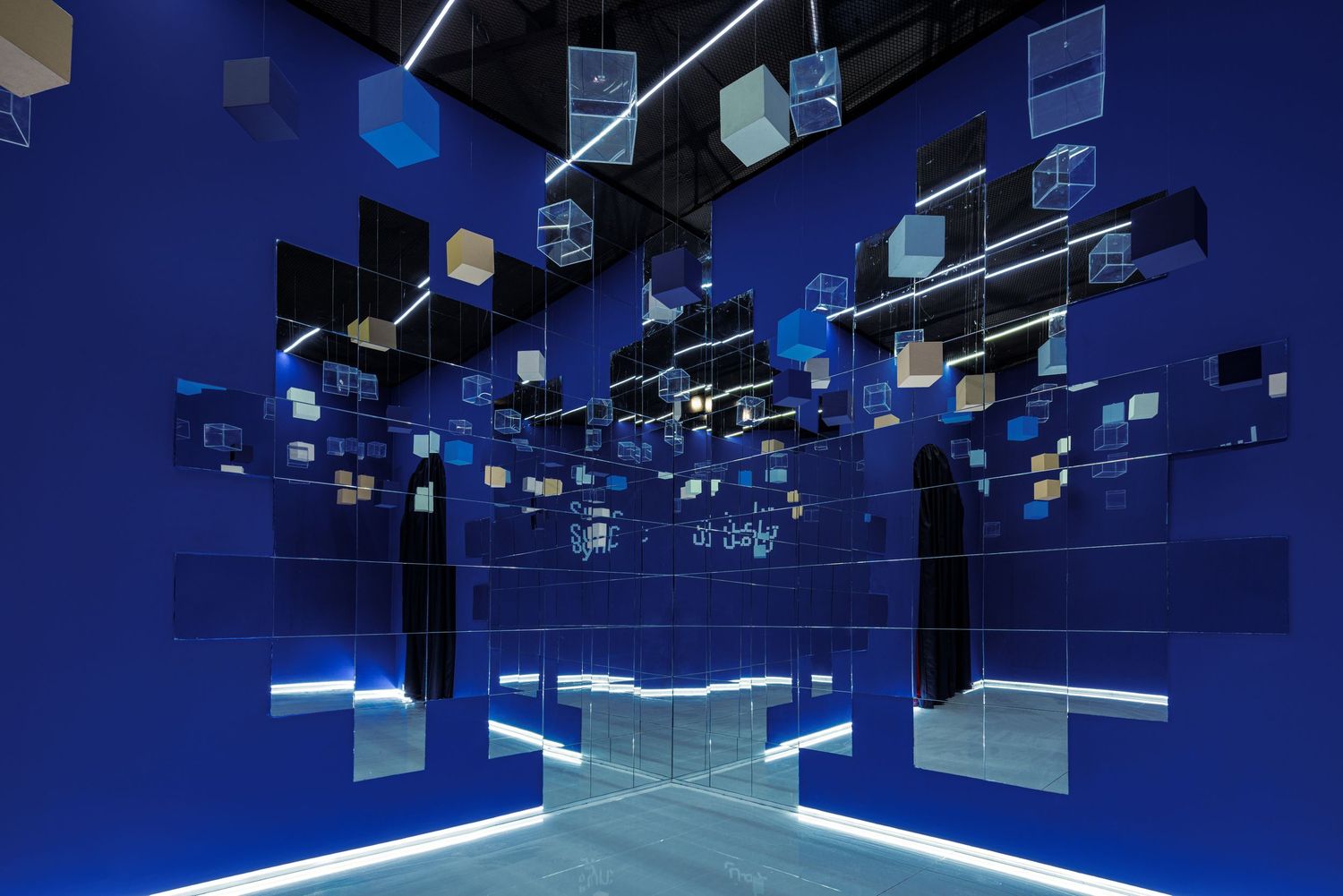 Immersive blue room installation with floating geometric cube sculptures and mirror walls creating infinite reflections.