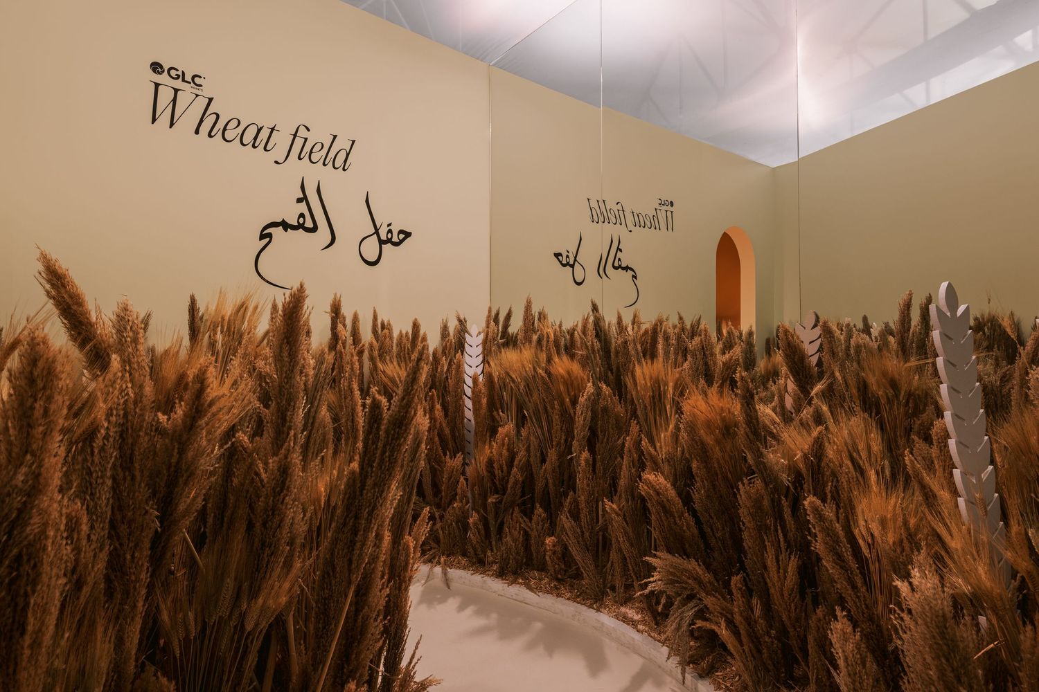 Indoor wheat field installation with Arabic and English Wheat Field text on beige wall display.