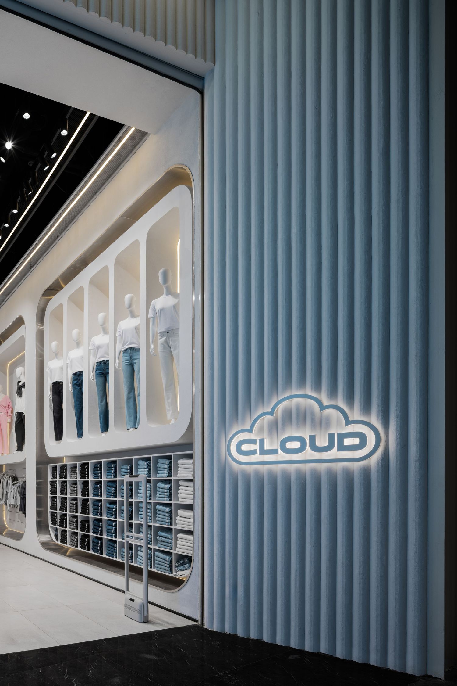 Cloud-themed retail store entrance with blue fluted wall panel, illuminated cloud logo sign, and white display niches.