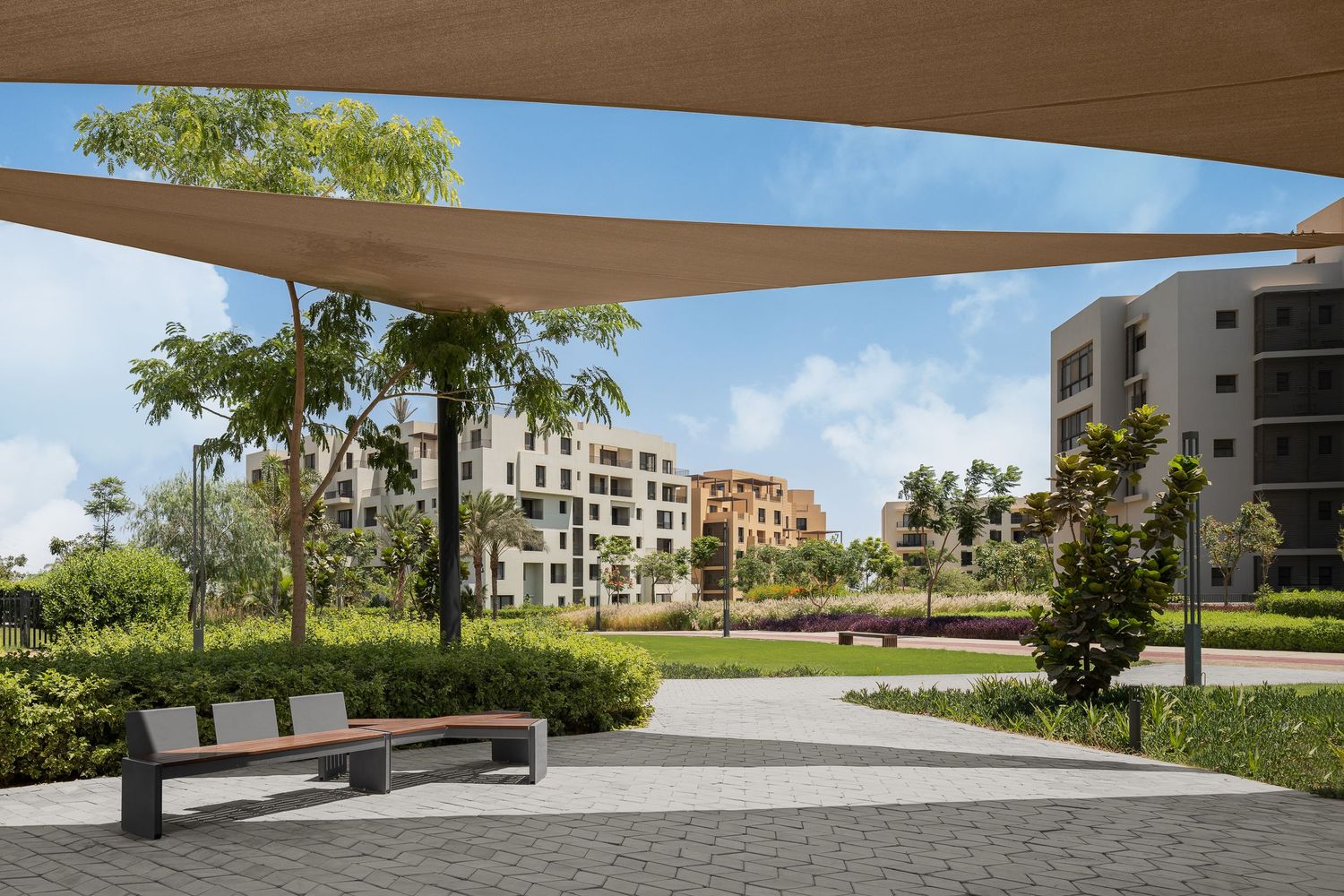 Modern outdoor seating area with shade sails, benches, and manicured gardens in an upscale residential community.