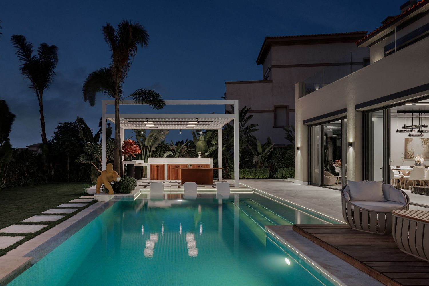 Elegant outdoor pool area of a modern villa at night with pergola, palm trees, and warm interior lighting.