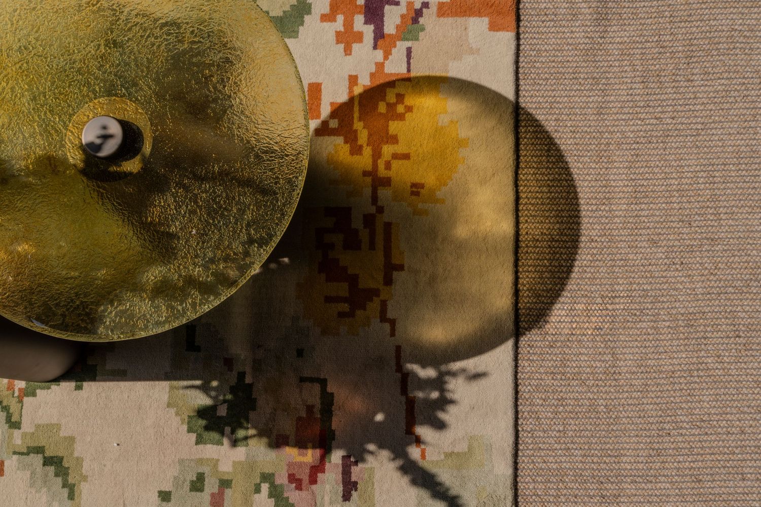 Overhead view of brass decorative objects casting shadows on colorful geometric patterned rug.