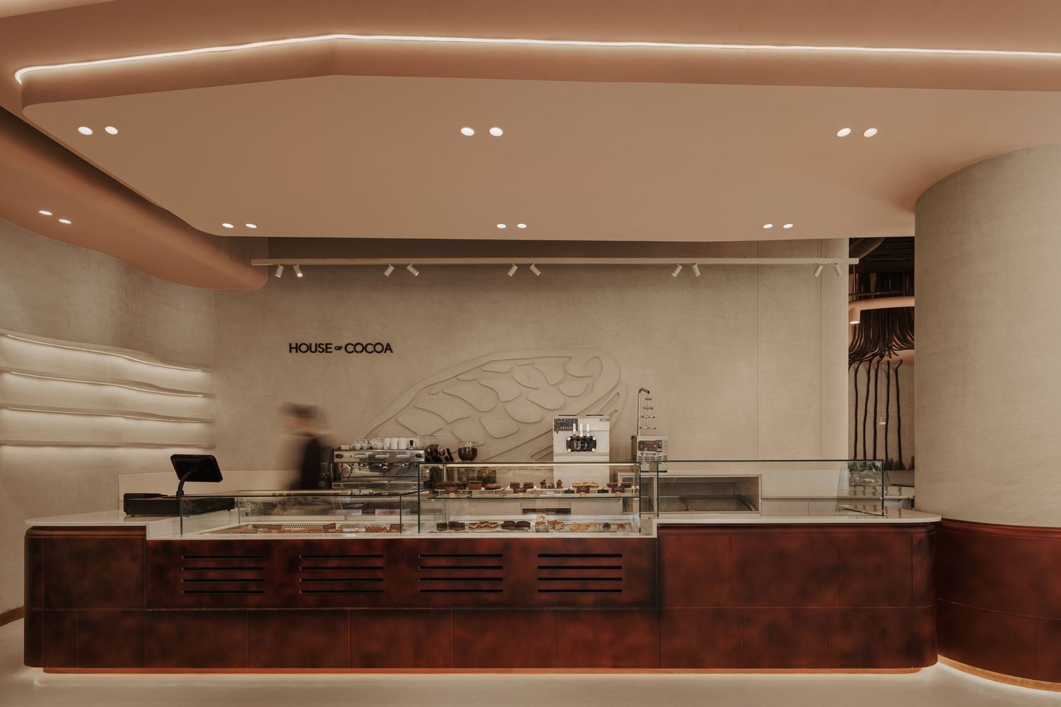 House of Cocoa cafe counter with dark wood display case and espresso machine.