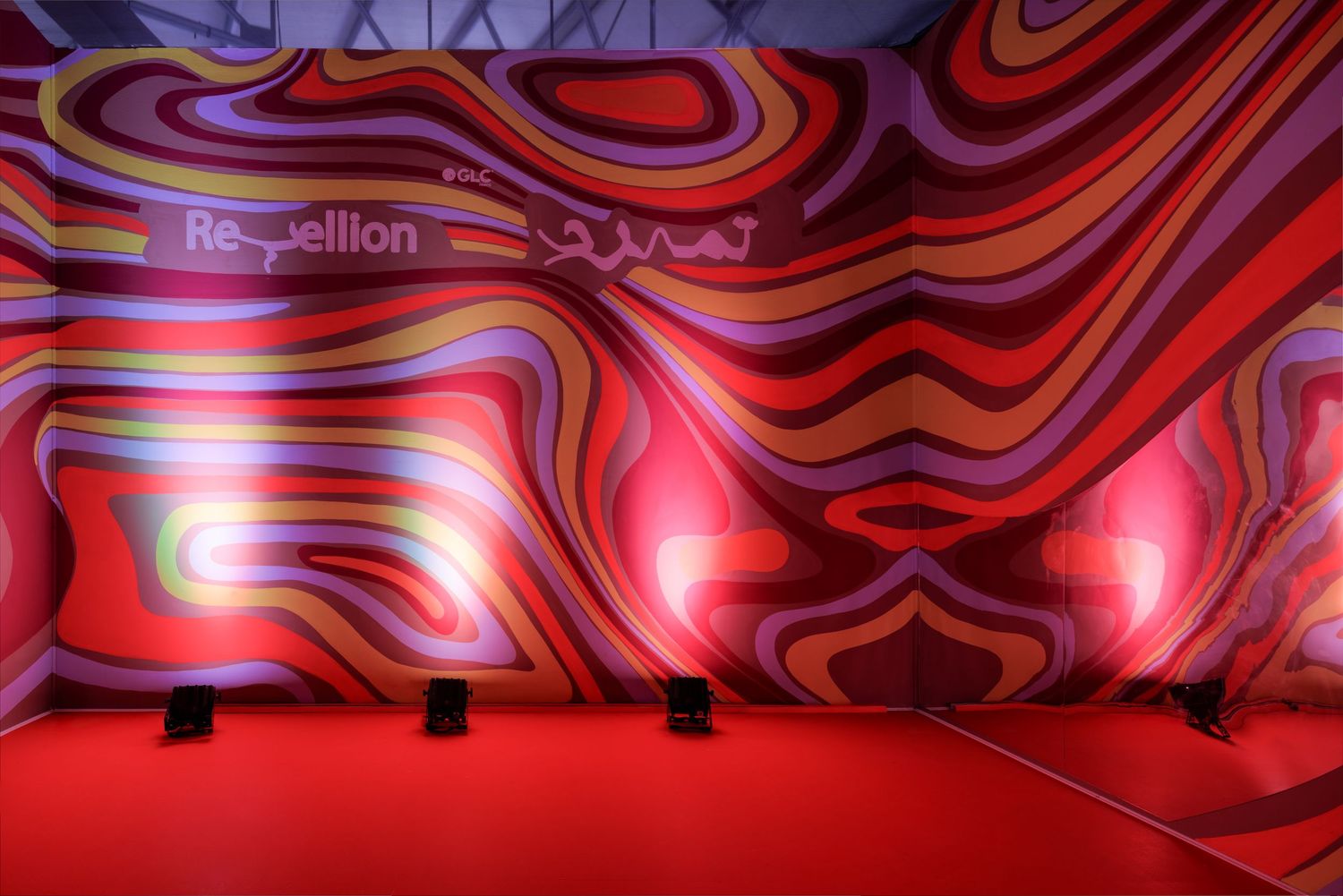 Vibrant psychedelic swirling red and purple mural wall with Re-bellion text in an exhibition space.
