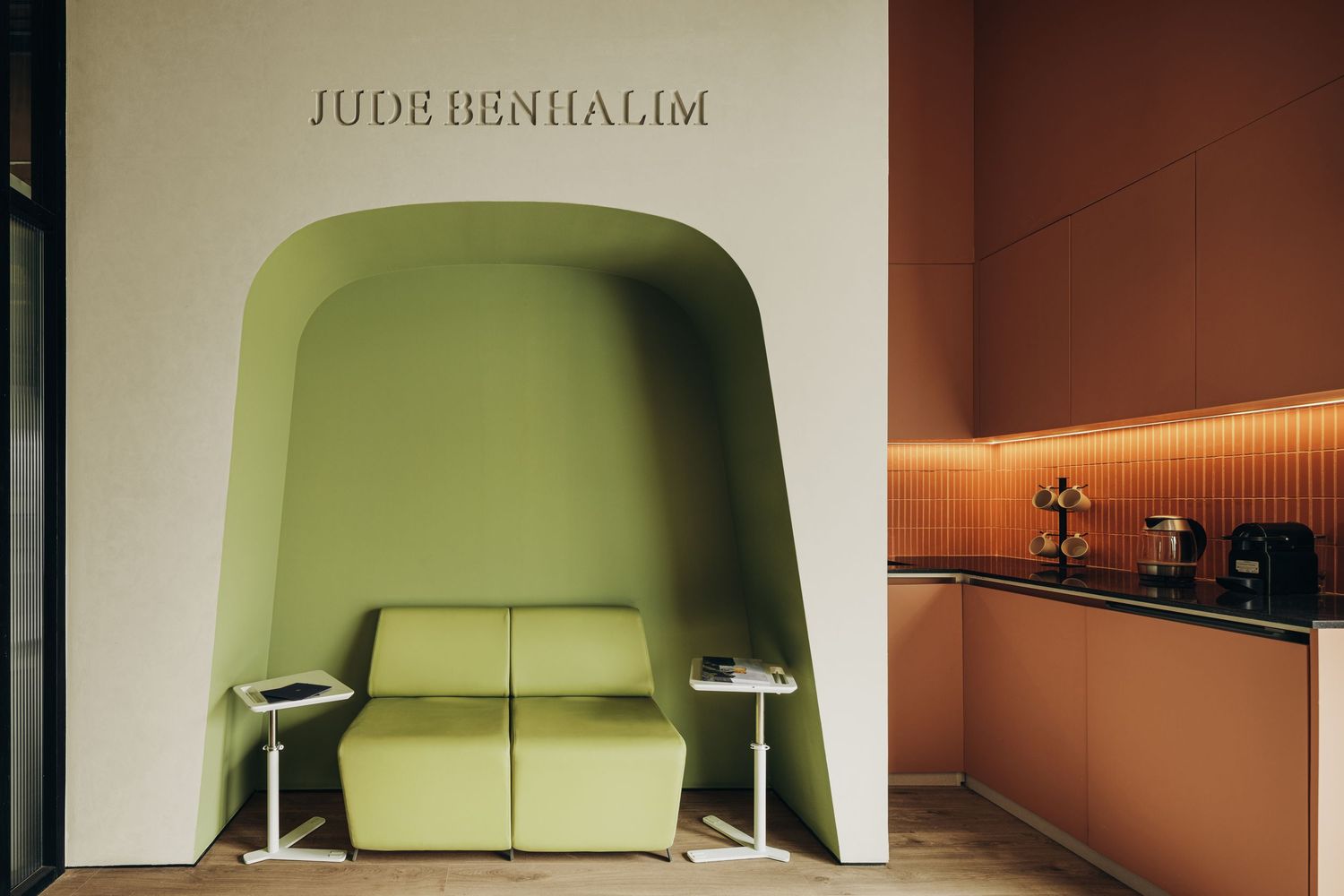 Jude Benhalim boutique lounge with green arched alcove sofa, terracotta wall, and coffee bar area.
