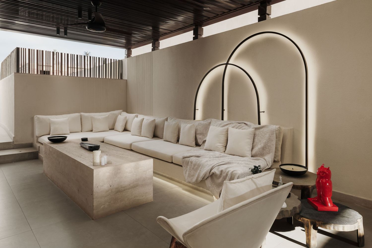Spacious neutral living room with oversized sectional sofa, arched floor lamp, and red accent sculpture.